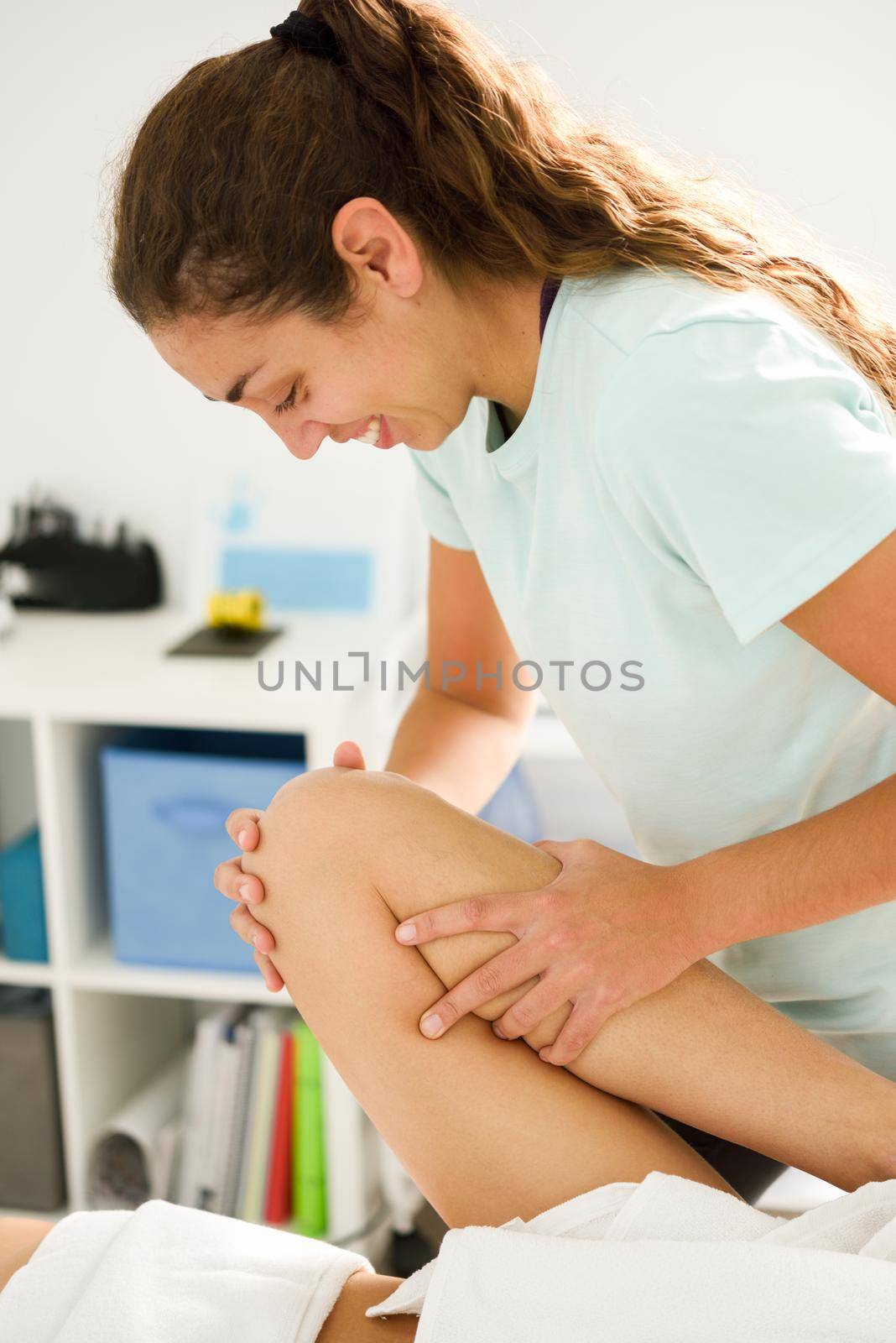 Medical massage at the leg in a physiotherapy center. Female physiotherapist inspecting her patient.