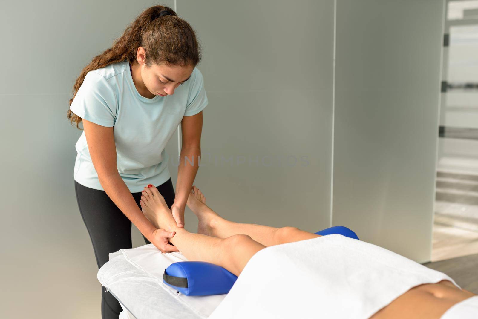 Medical massage at the foot in a physiotherapy center. Female physiotherapist inspecting her patient.
