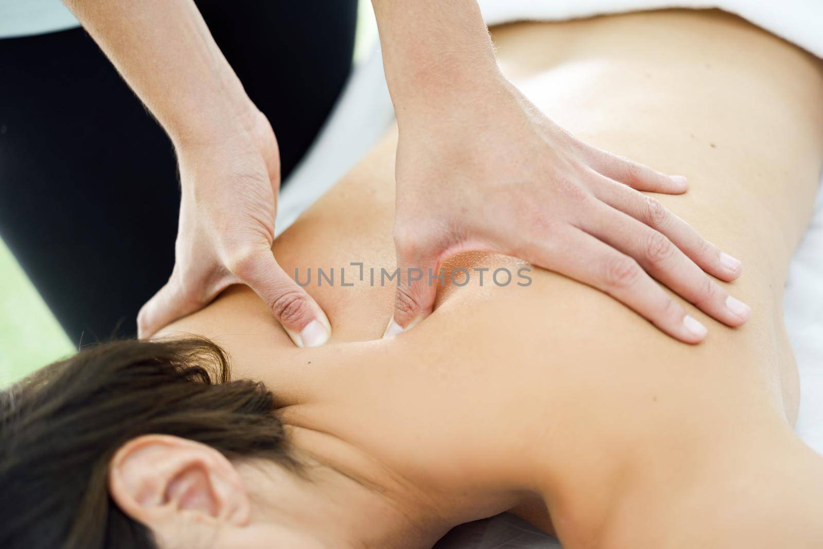 Young woman receiving a back massage in a spa center. Female patient is receiving treatment by professional therapist.