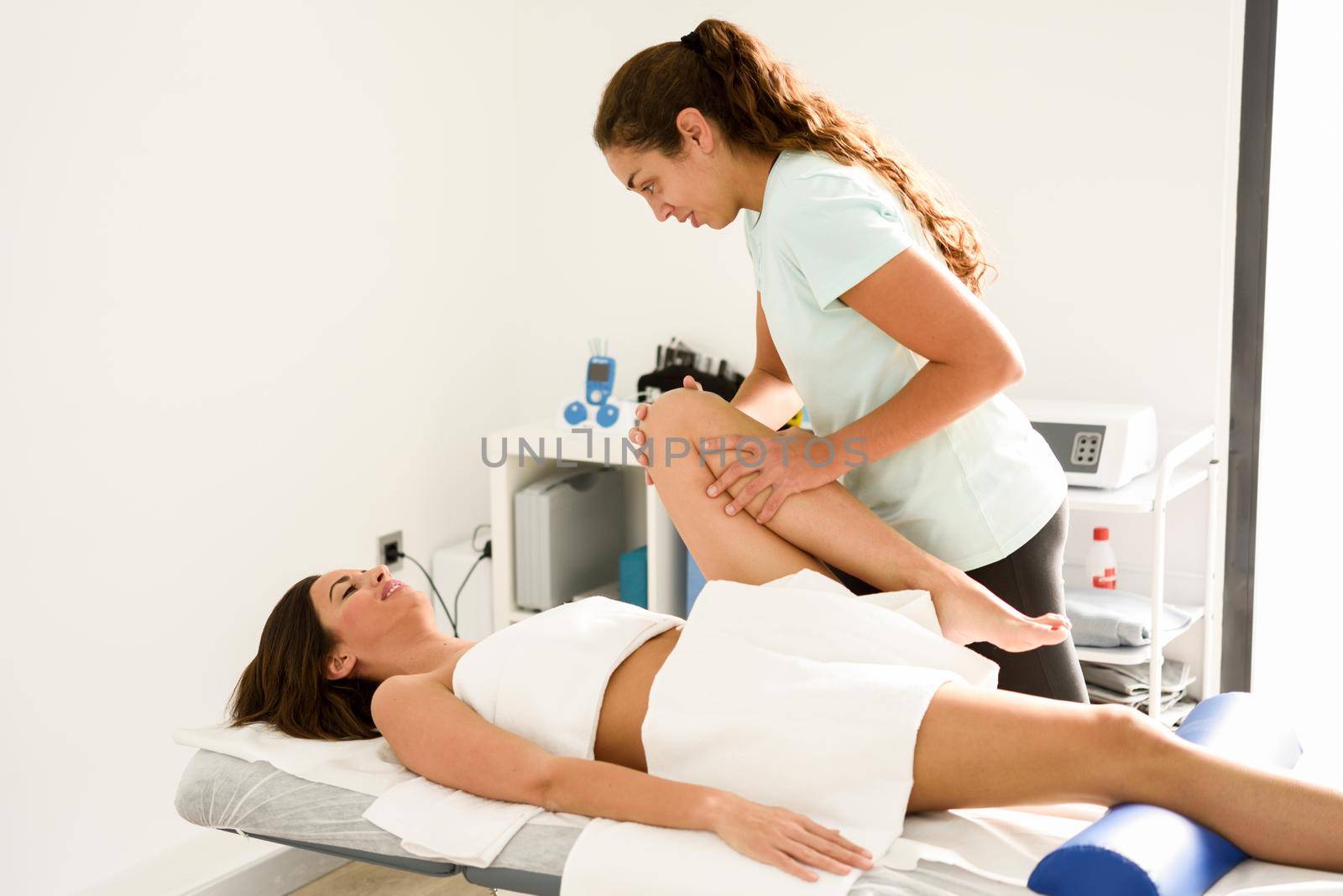 Medical massage at the leg in a physiotherapy center. Female physiotherapist inspecting her patient.