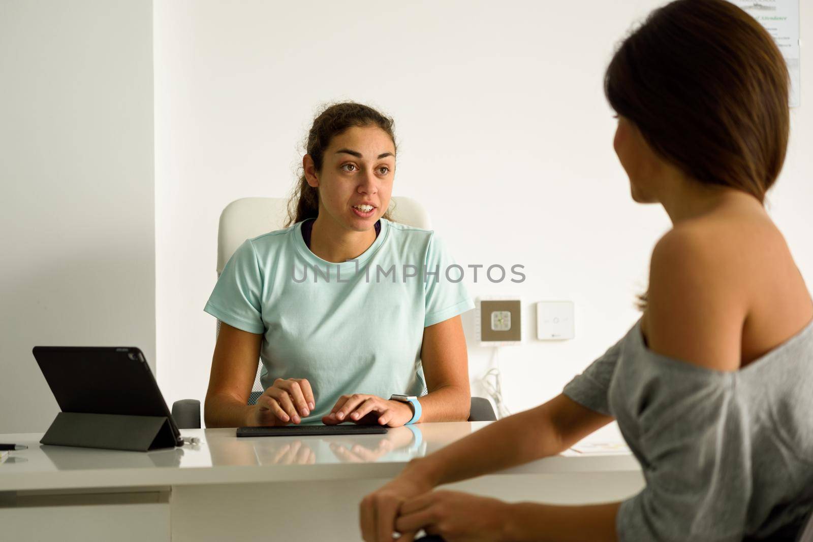 Female physiotherapist explaining diagnosis to her patient. Brunette woman having consultation with girl in medical office.