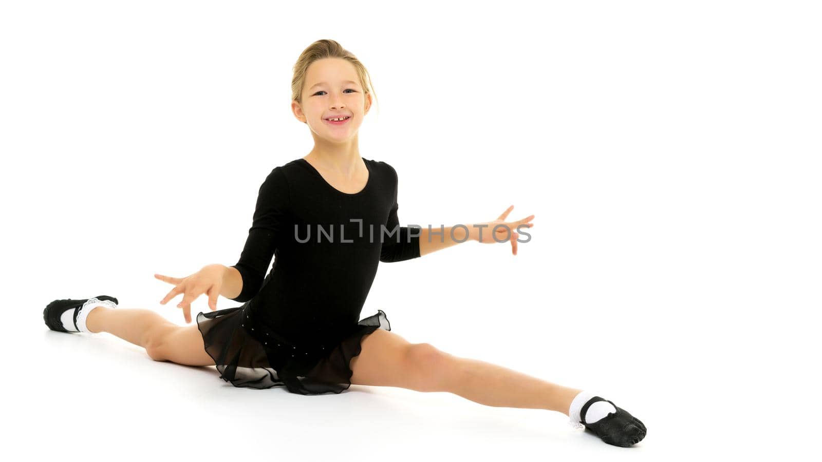 A little girl performs a gymnastic twine. The concept of fitness and sports. Isolated on white background.