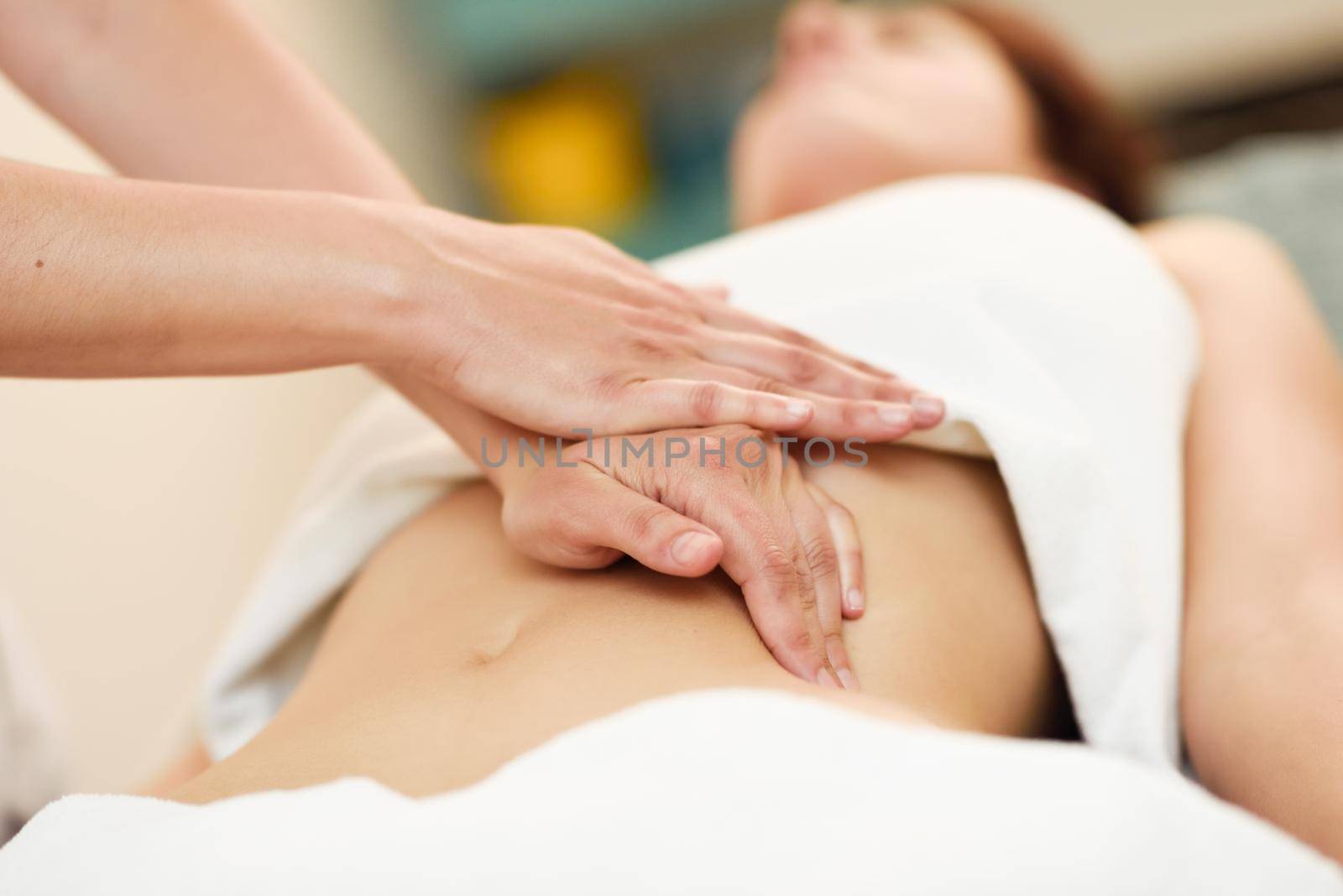 Therapist applying pressure on belly. Woman receiving massage at spa salon. Hands massaging female abdomen