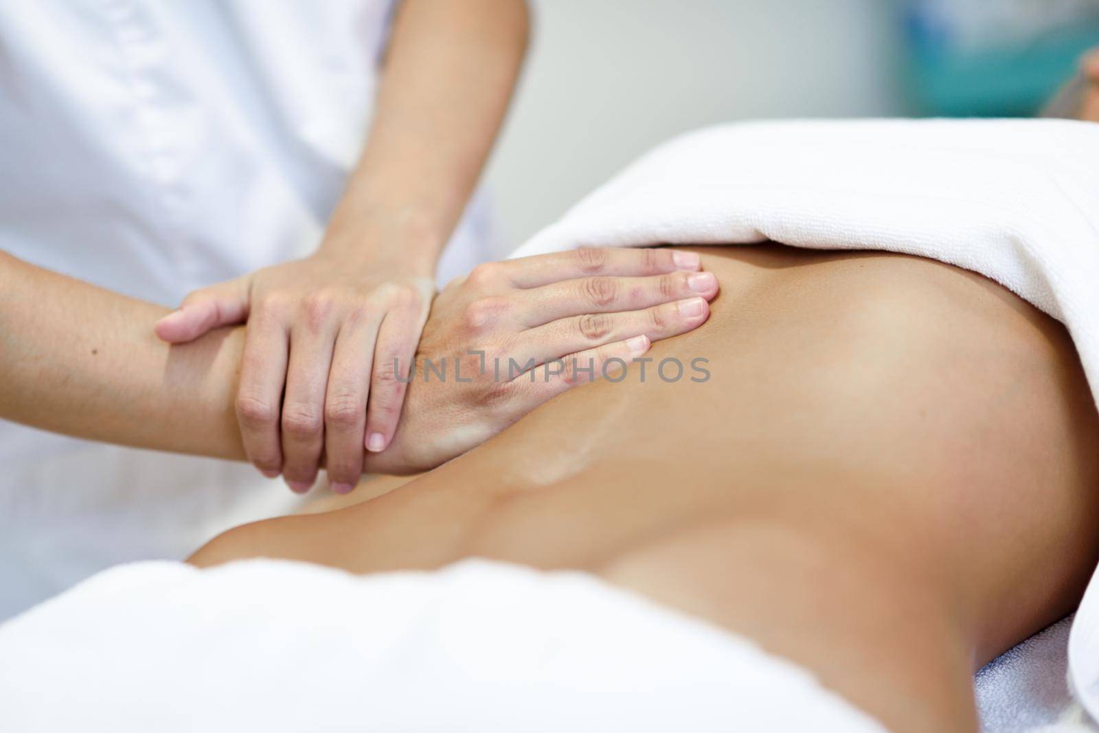 Hands massaging female abdomen.Therapist applying pressure on belly. Woman receiving massage at spa salon