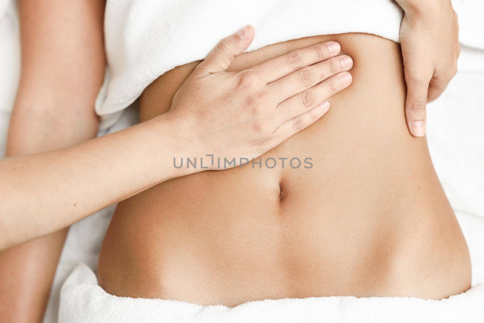 Top view of hands massaging female abdomen.Therapist applying pressure on belly. Woman receiving massage at spa salon