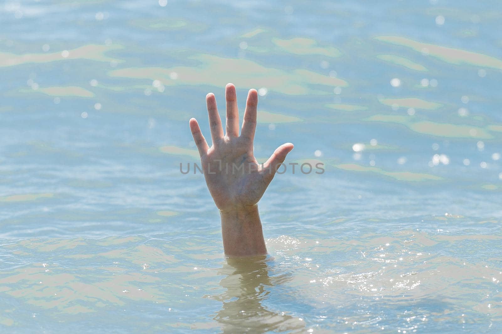 A hand from under the water of a drowning girl, help and urgent rescue of a person during a dangerous swimming, sos.