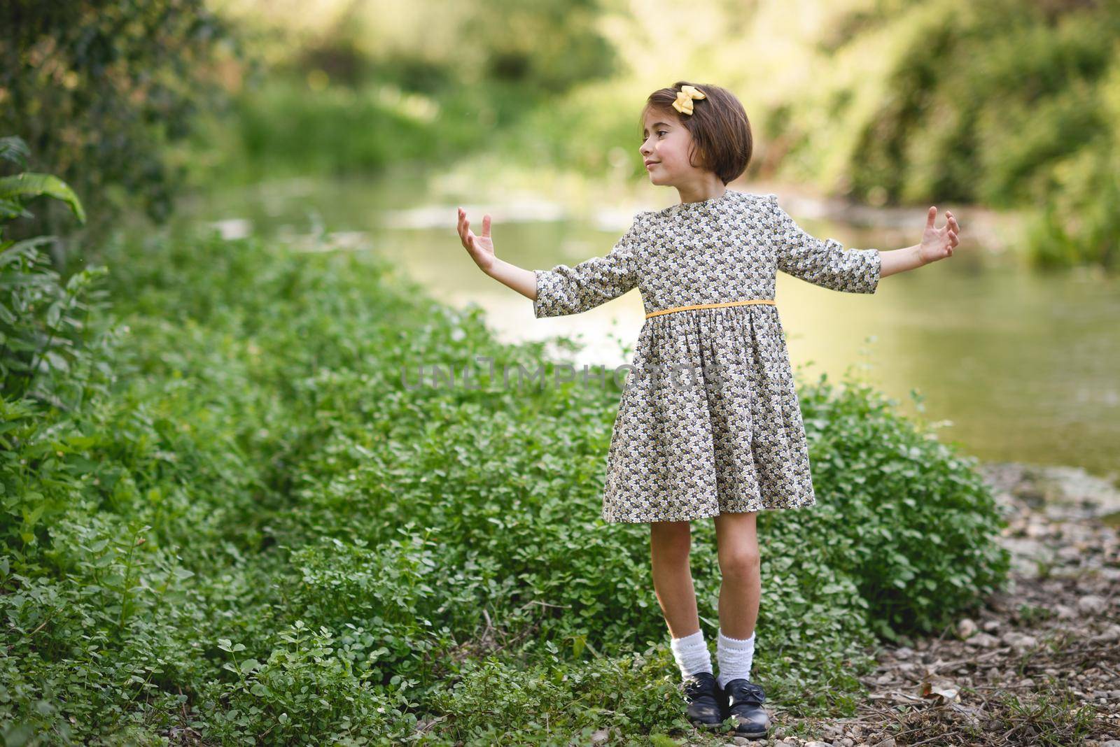 Little beautiful girl in nature stream wearing beautiful dress