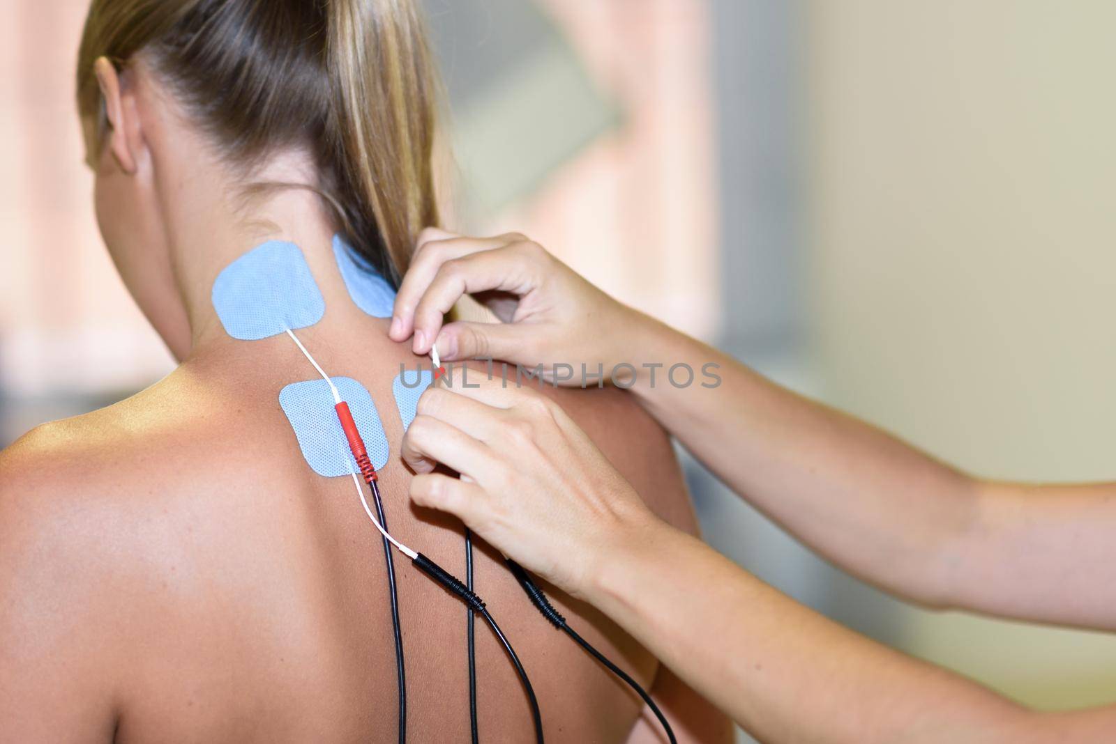 Electro stimulation in physical therapy to a young woman. Medical check at the shoulder in a physiotherapy center.
