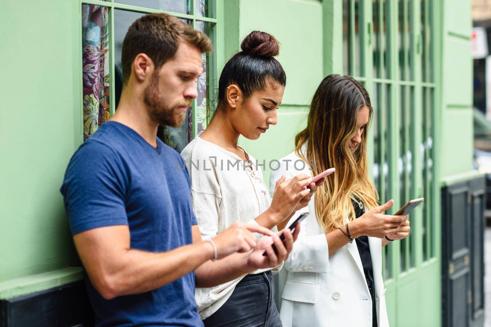 Multiracial group of people looking down at smart phone, concepts about technology addiction and youth