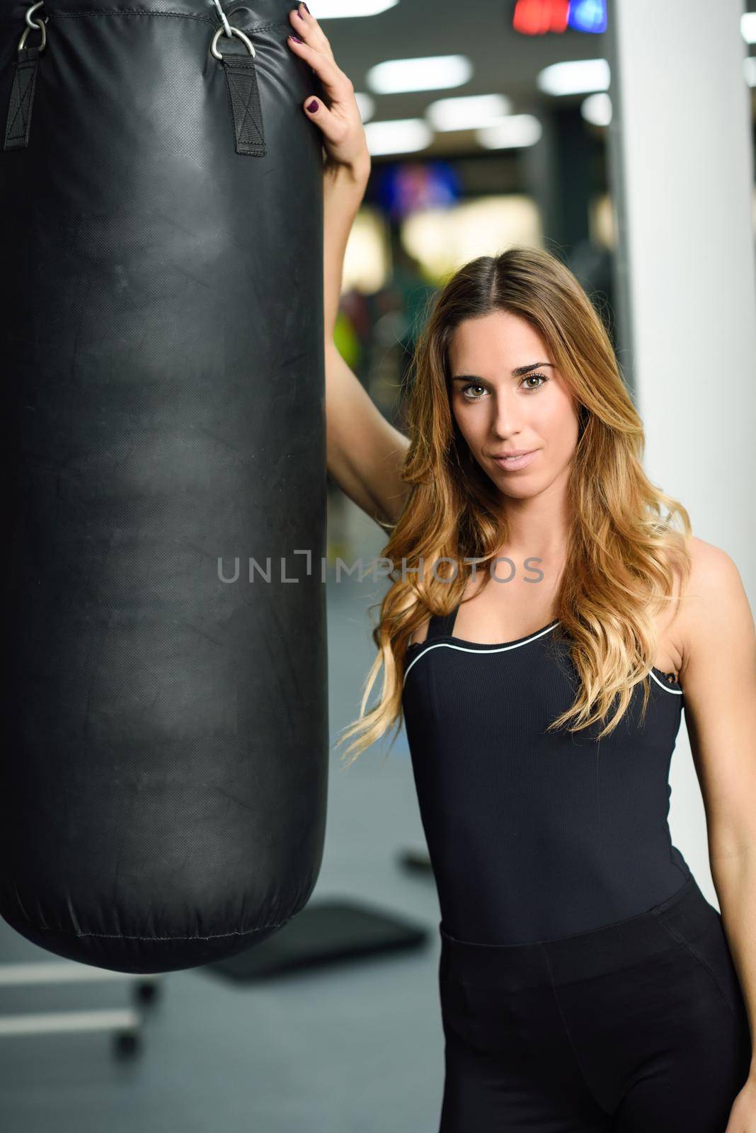 Female personal trainer with punching bag in a gym. Woman wearing sportswear clothes.