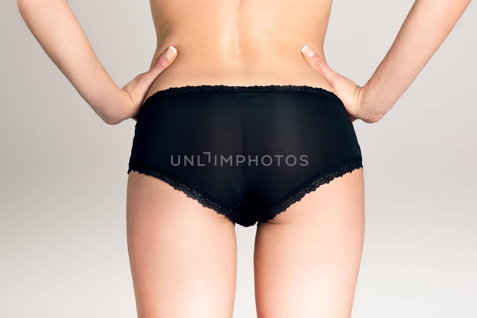 Female ass wearing black panties, white background