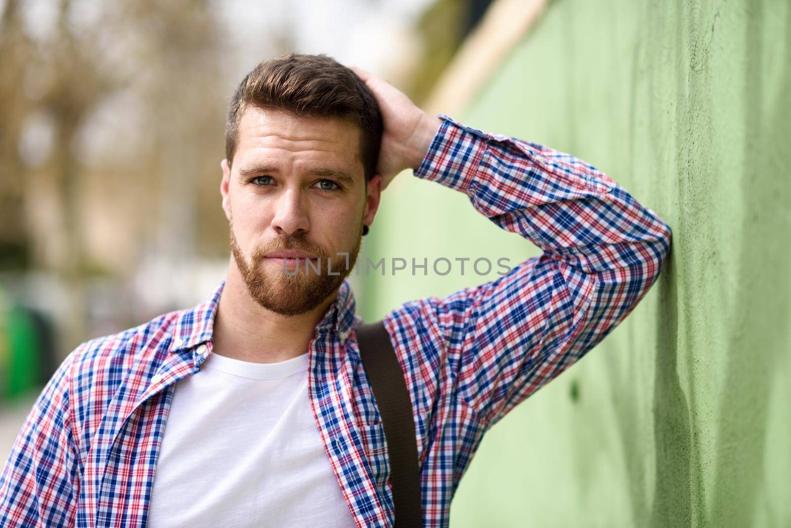 Attractive young man standing in urban background. Guy looking at camera wearing casual clothes. Lifestyle concept.