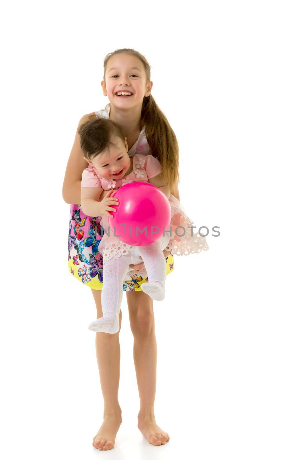 Cute Happy Girls Laughing and Playing Together with Pink Balloon, Teen Girl Holding Cute Toddler Sister on Her Hands, Two Adorable Happy Children Having Fun on Isolated on White Background