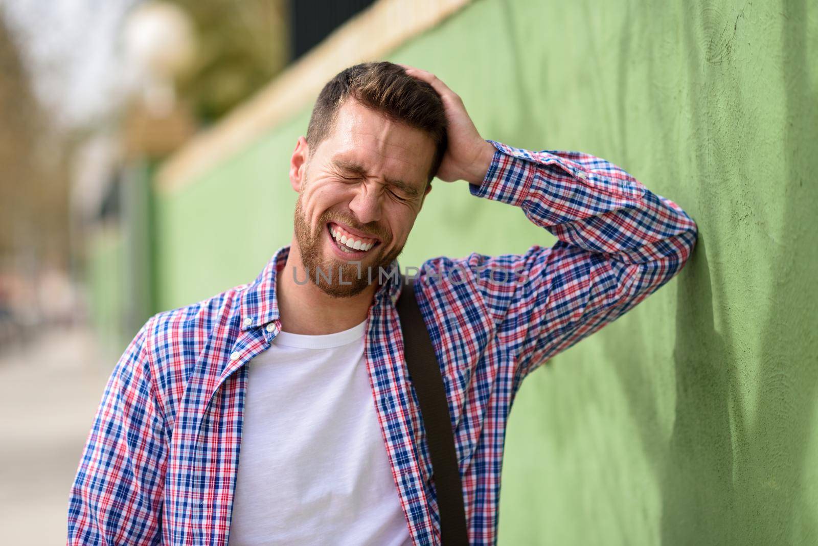 Attractive young man laughing outdoors. Lifestyle concept. by javiindy