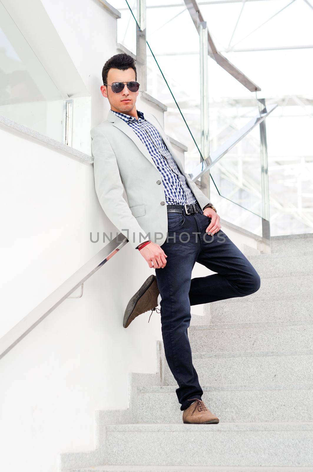Portrait of a young handsome man, model of fashion, wearing tinted sunglasses