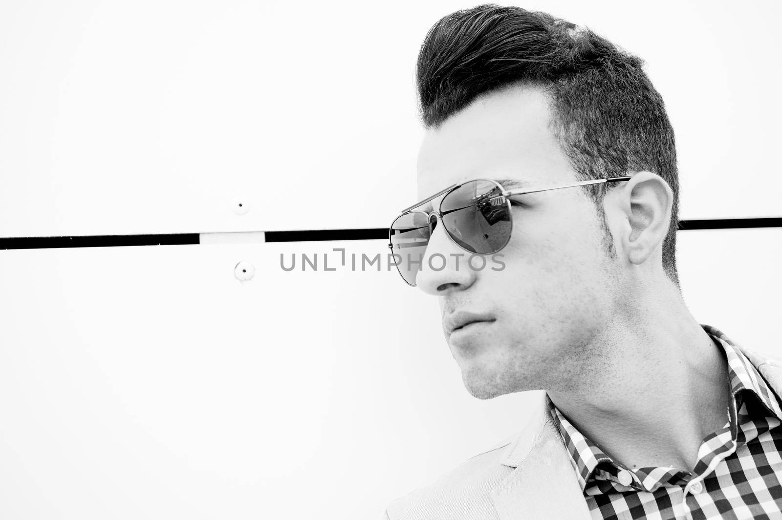 Portrait of a young handsome man, model of fashion, wearing tinted sunglasses