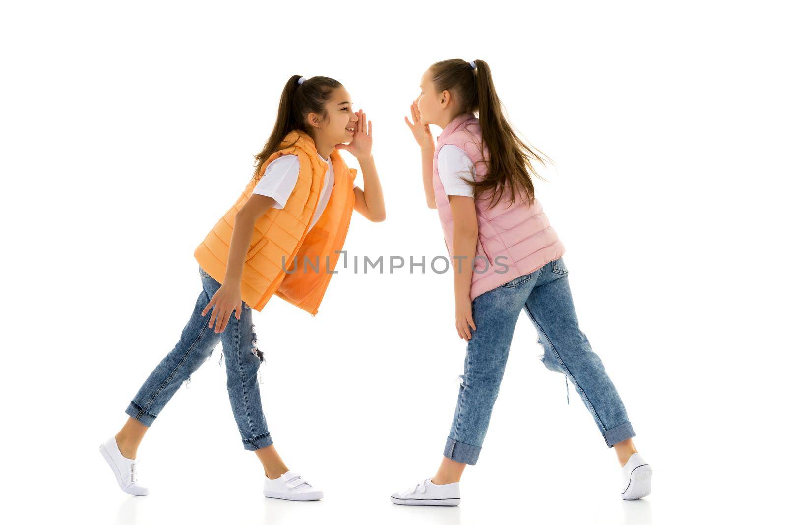 Two girls telling a secret and expressing surprise isolated on white