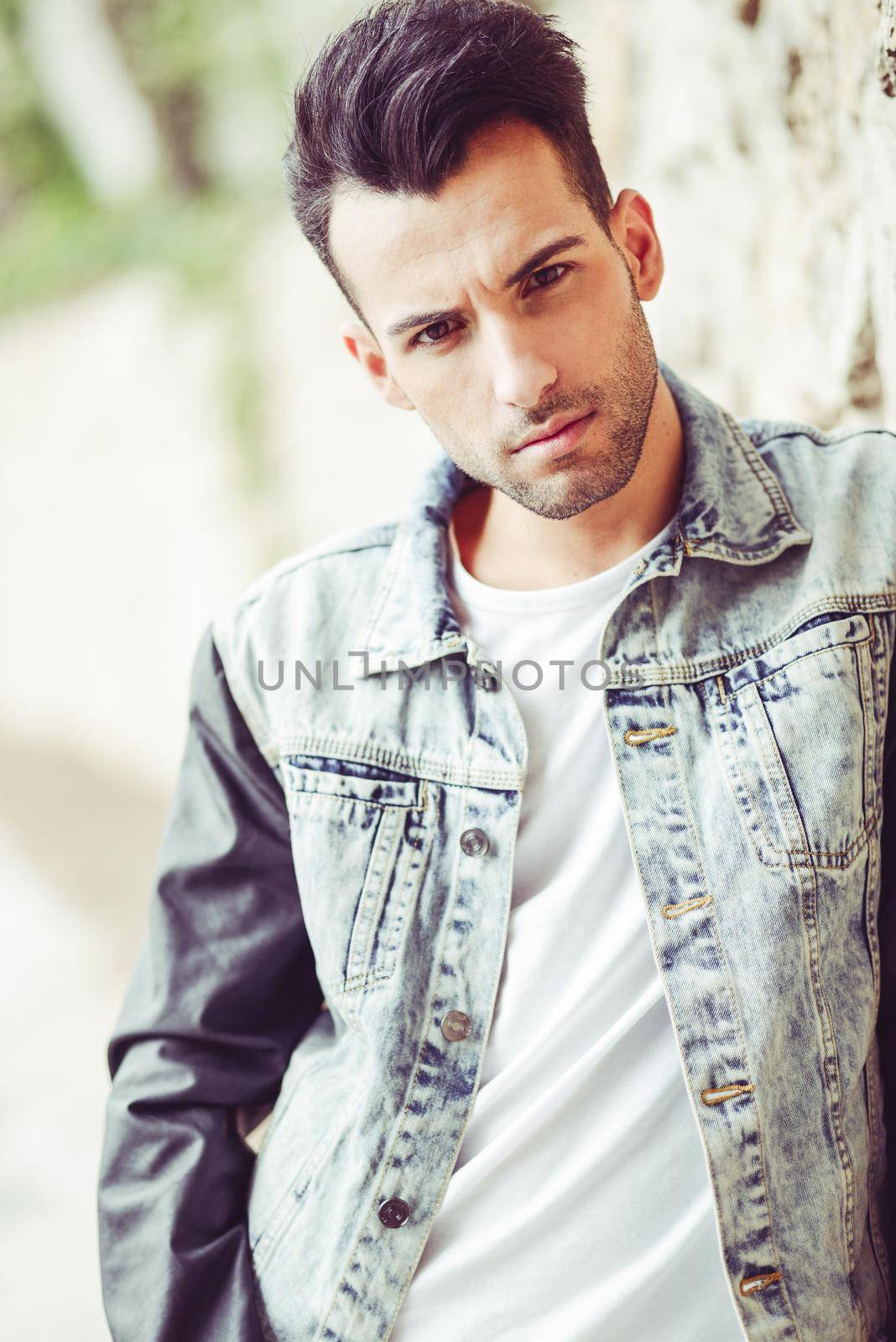 Portrait of a young handsome man, model of fashion, with modern hairstyle in urban background