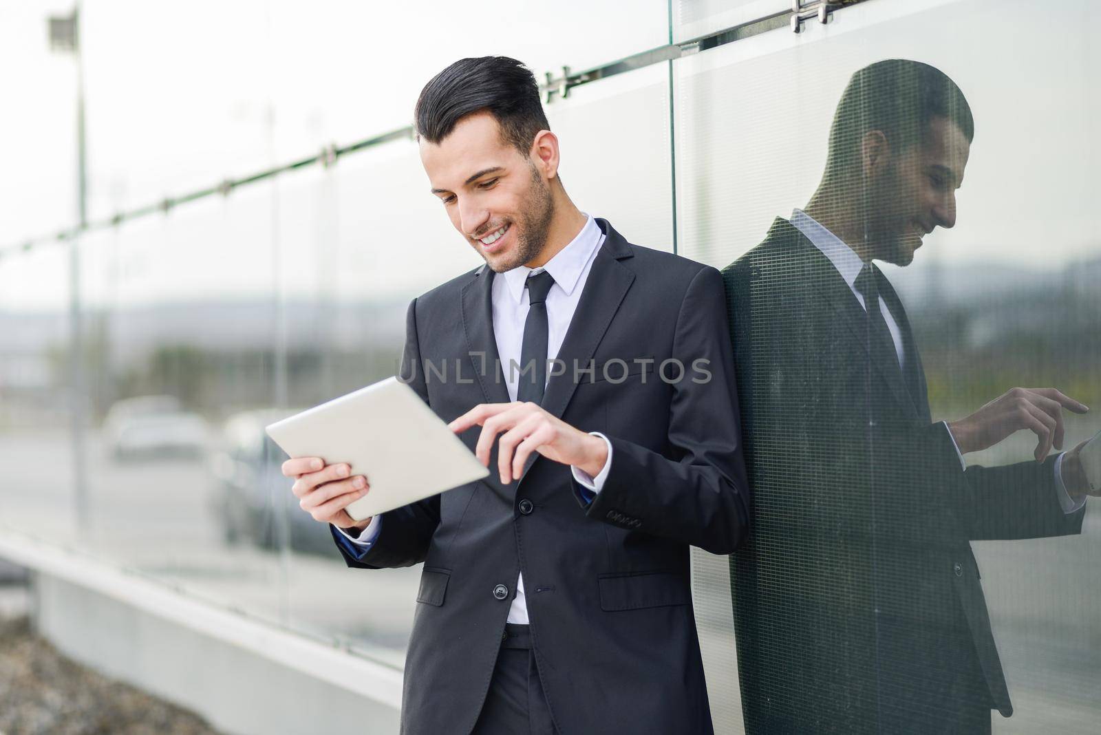 Portrait of attractive young businessman smiling with a tablet computer in an office building