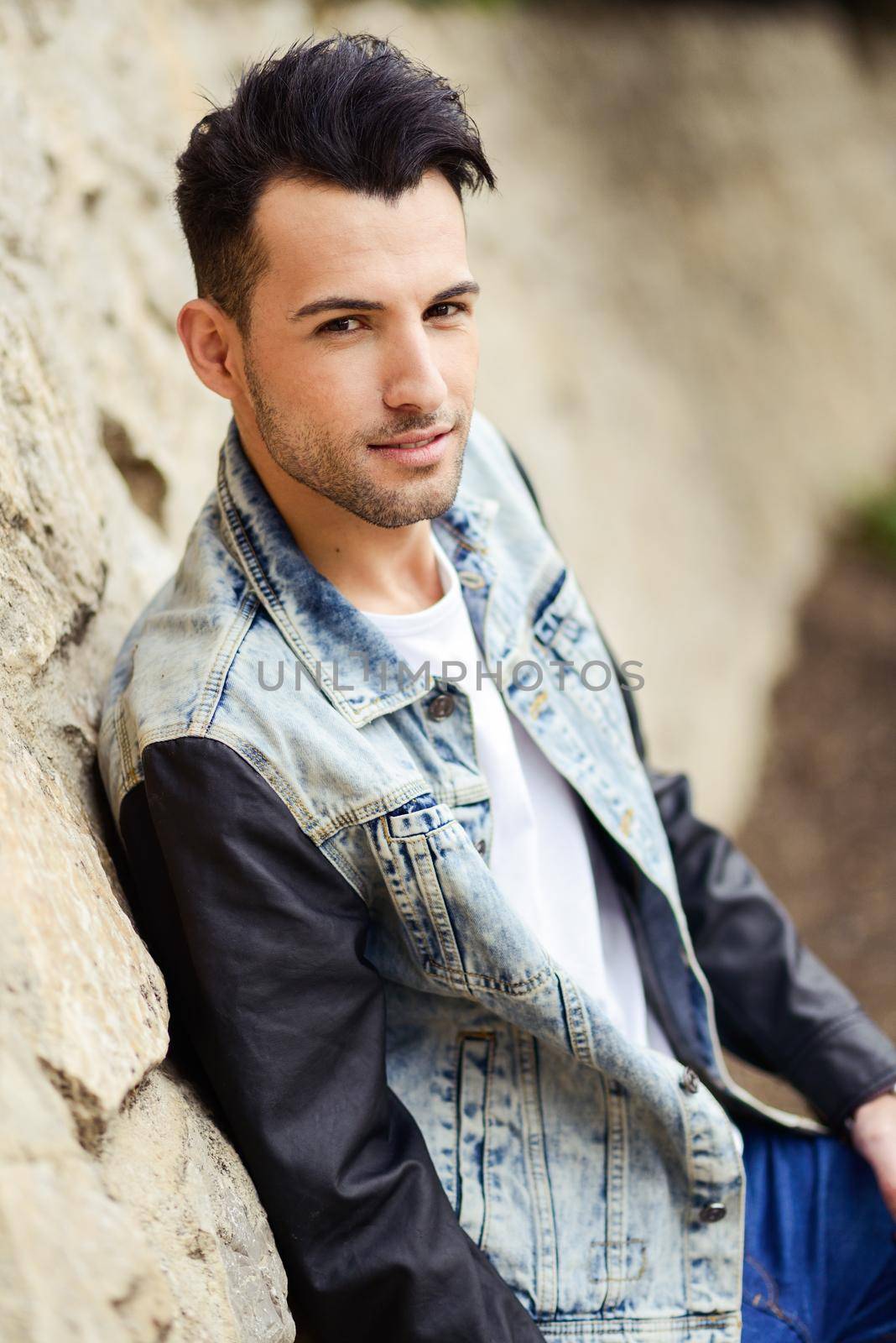 Portrait of a young handsome man, model of fashion, with modern hairstyle smiling in urban background