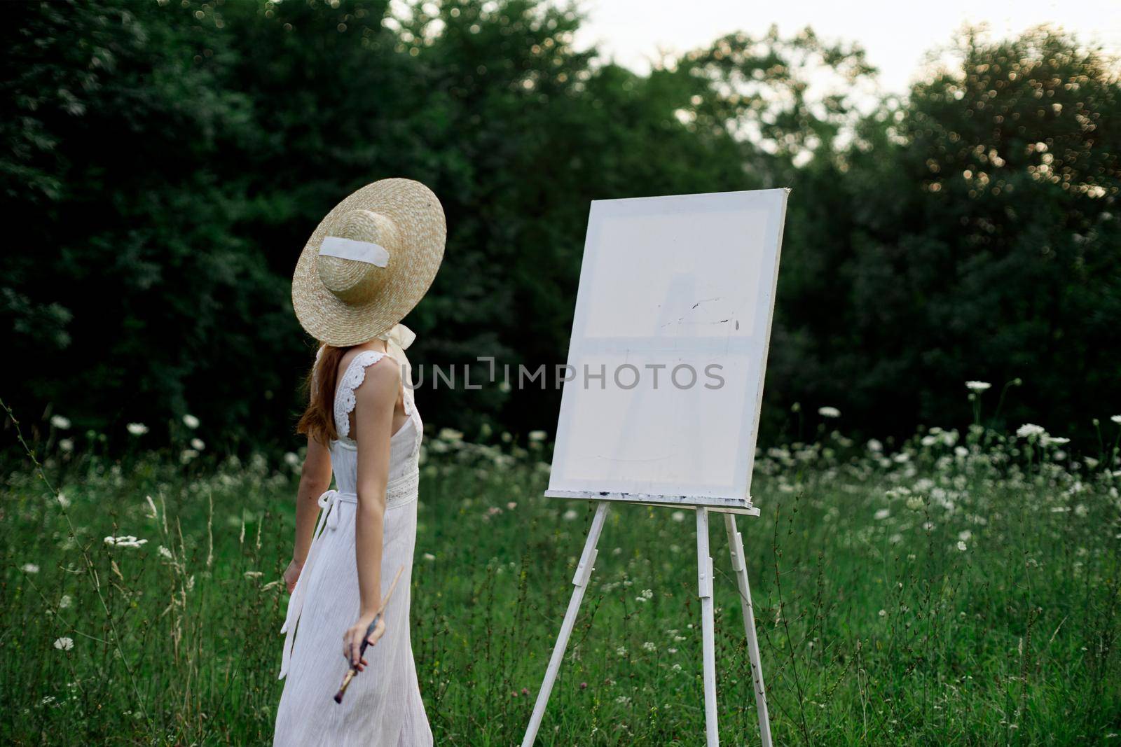 A woman in a white dress in a field with flowers paints a picture by Vichizh