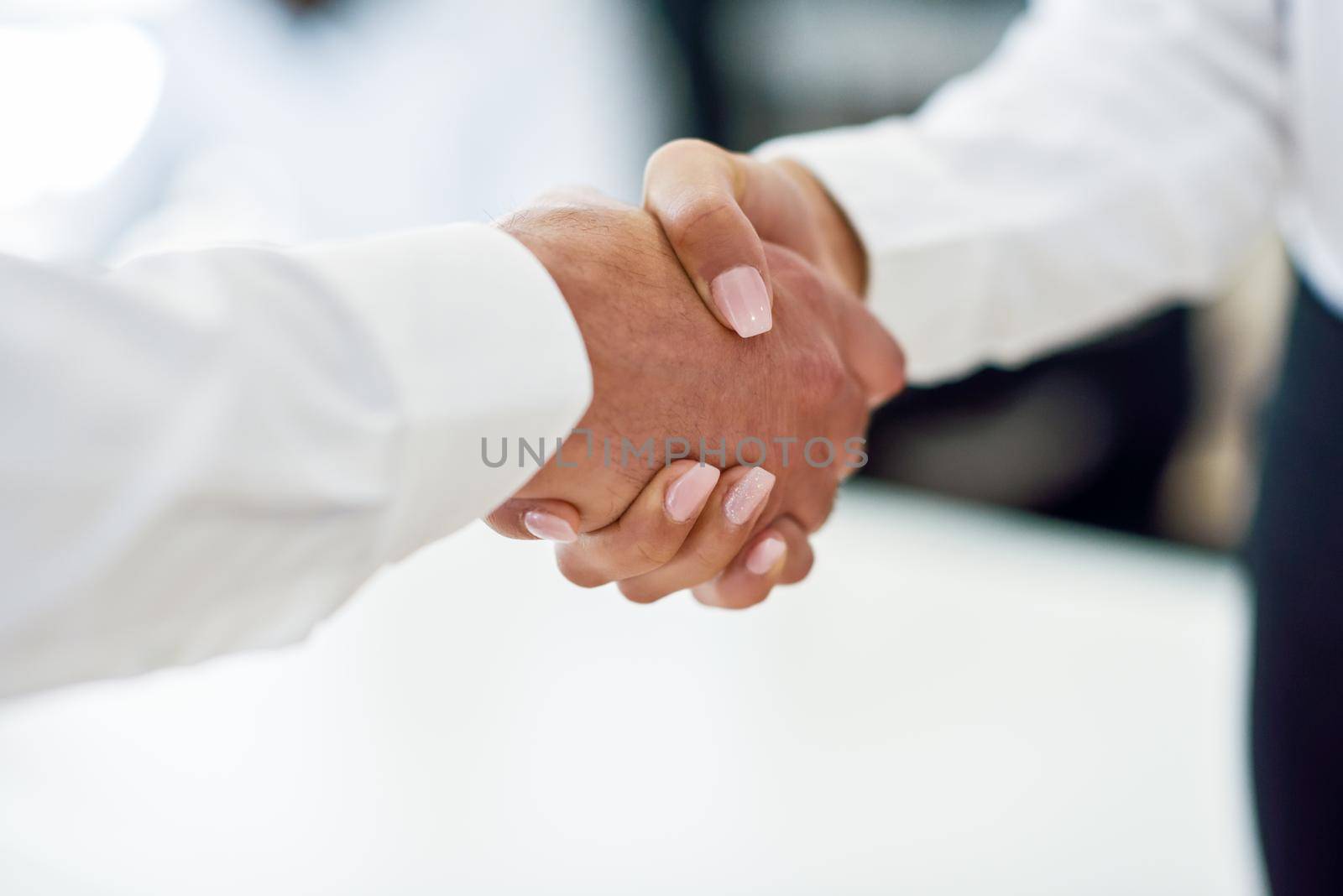 Caucasian businessman shaking hands with businesswoman wearing suit in a office. Close-up shot