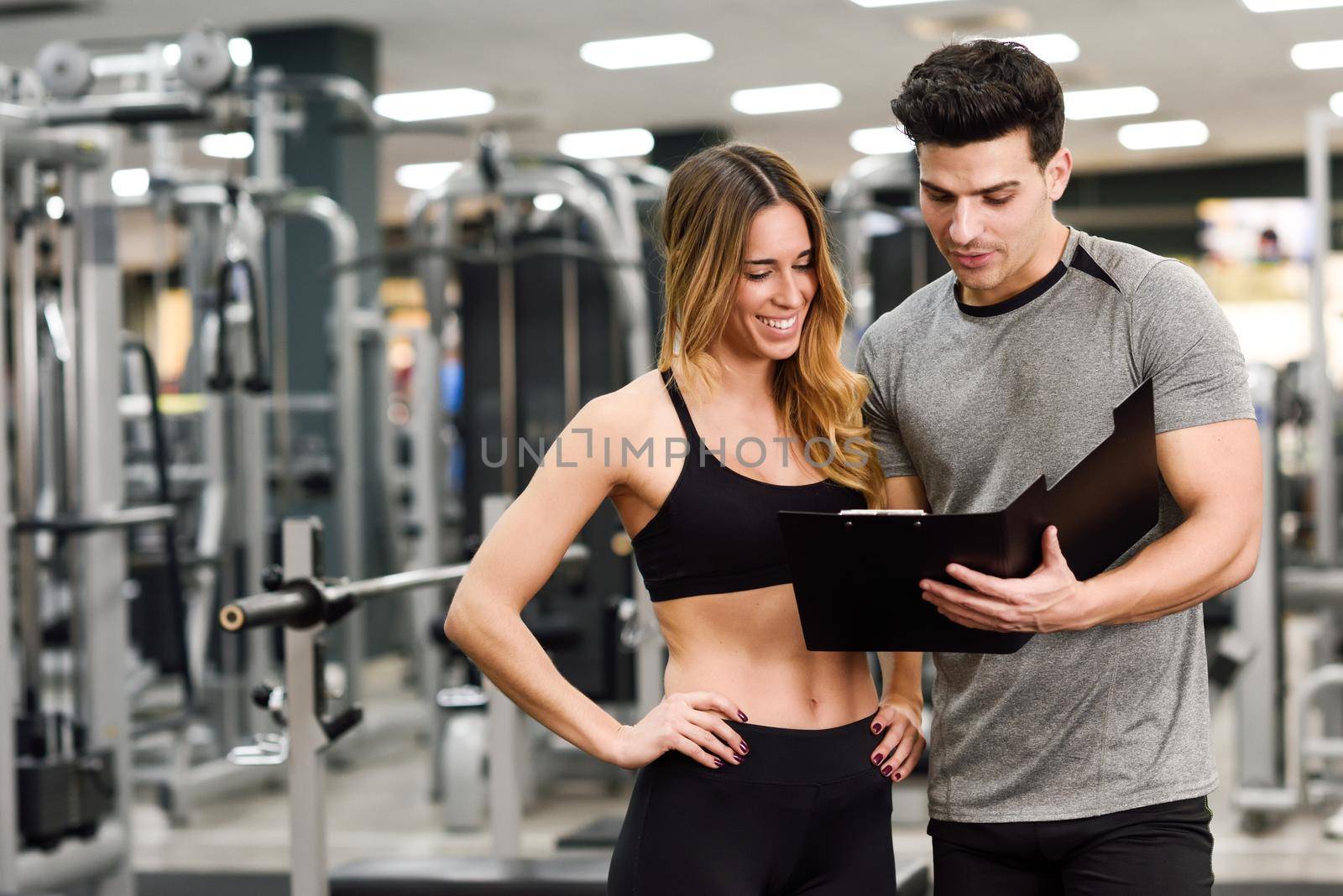 Personal trainer and client looking at her progress at the gym. Athletic man and woman wearing sportswear.