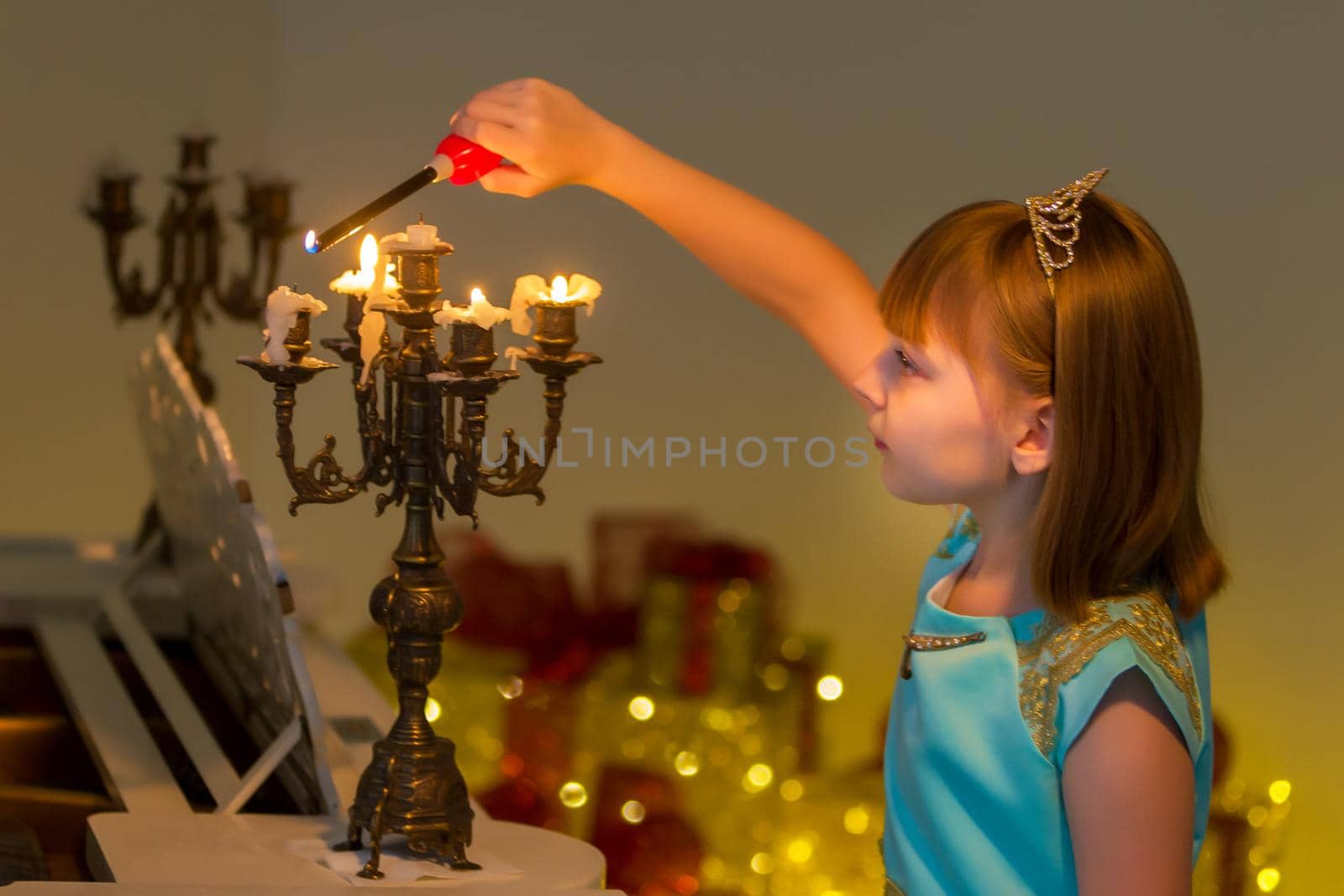 Little girl lights candles on Christmas night. by kolesnikov_studio