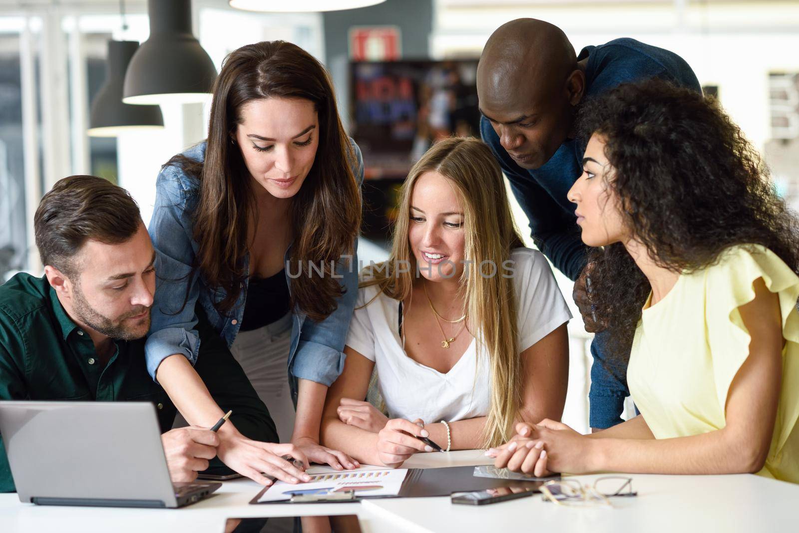 Multi-ethnic group of young men and women studying indoors. by javiindy