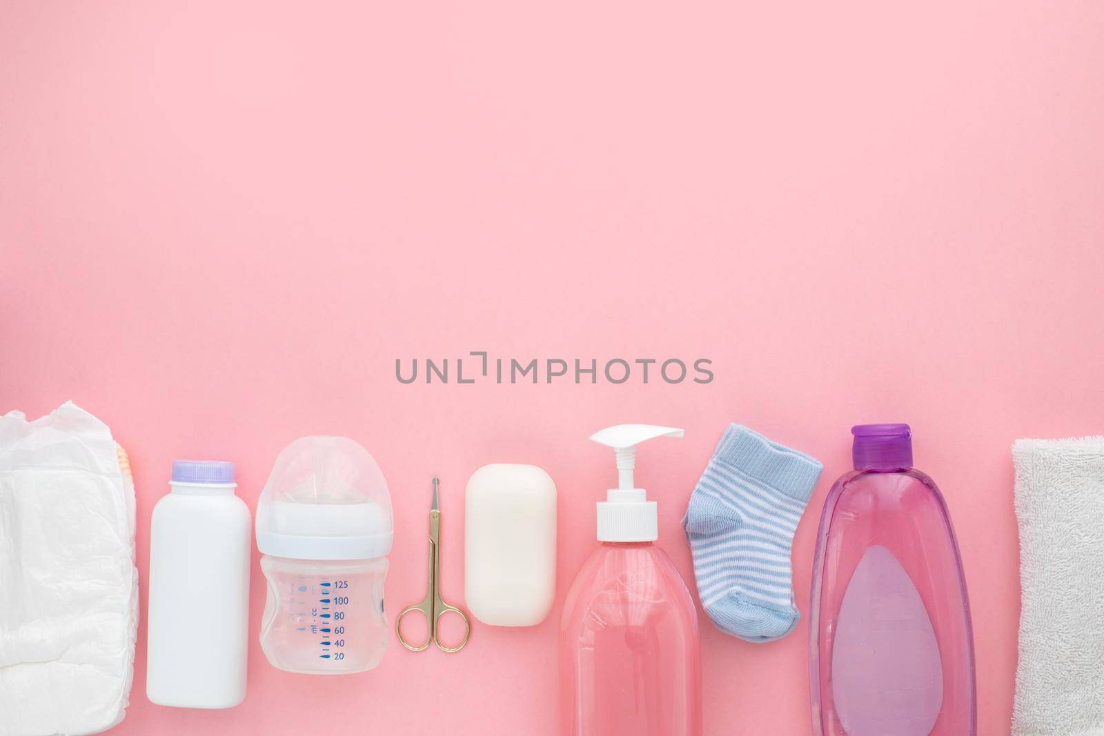 Set for a newborn nipple bottle diaper socks baby body slip pink background top view Children's hygiene