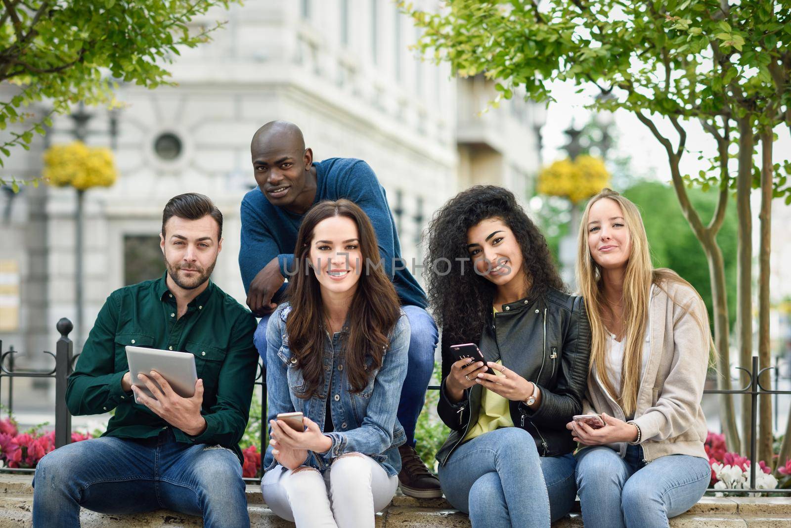 Multi-ethnic young people using smartphone and tablet computers outdoors by javiindy