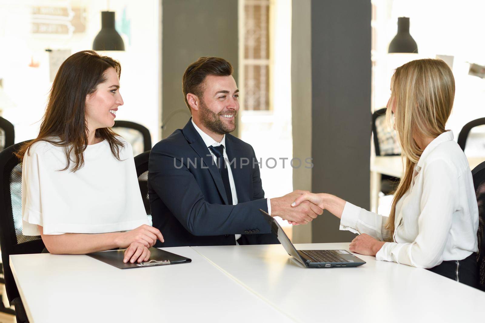 Smiling young couple shaking hands with an insurance agent by javiindy