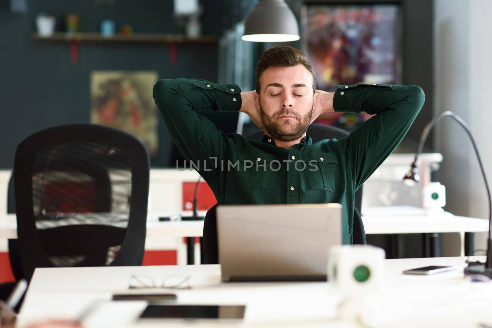 Young man studying with laptop computer on white desk. by javiindy