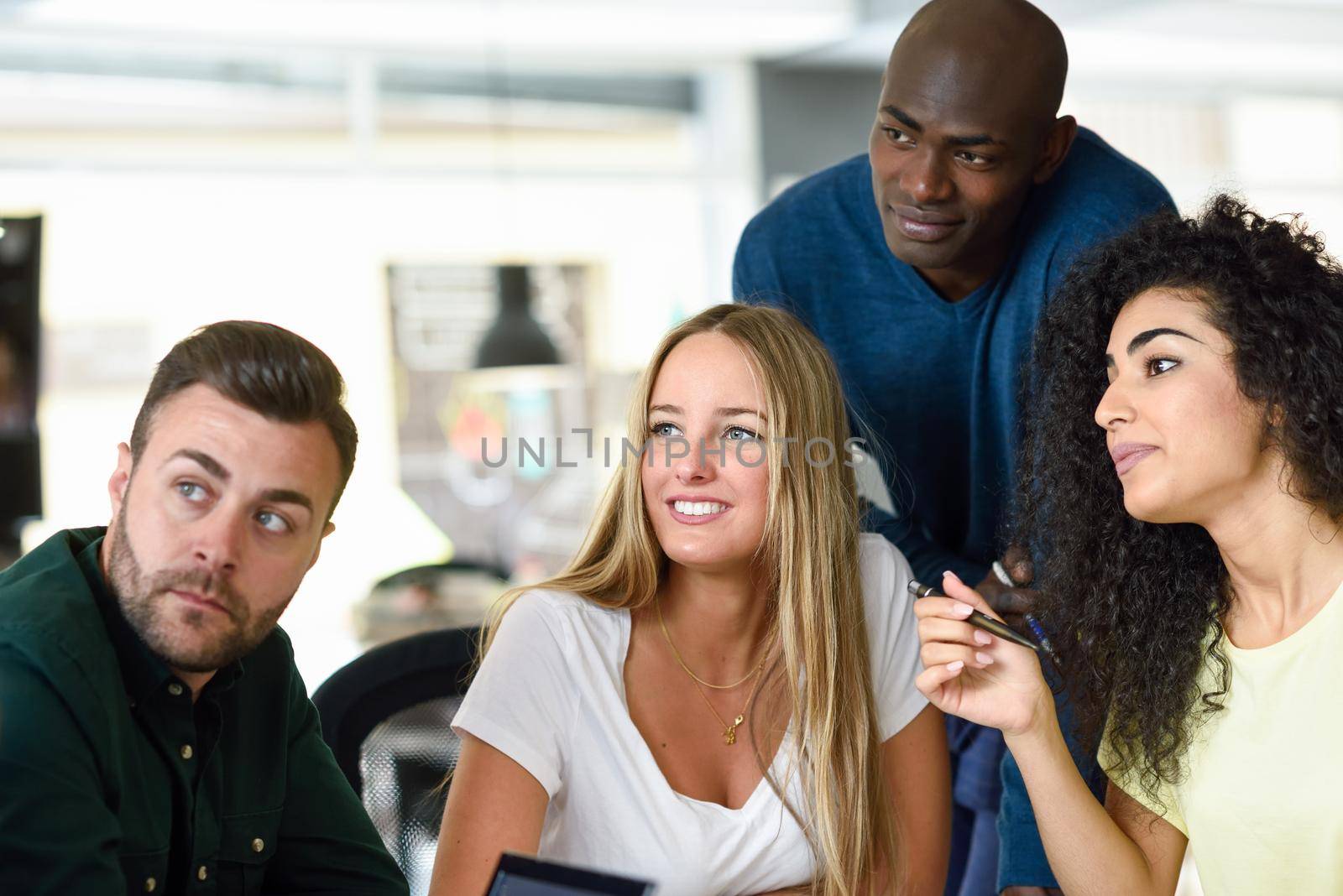Four young people working together. Beautiful men and women in a business meeting wearing casual clothes. Multi-ethnic group.