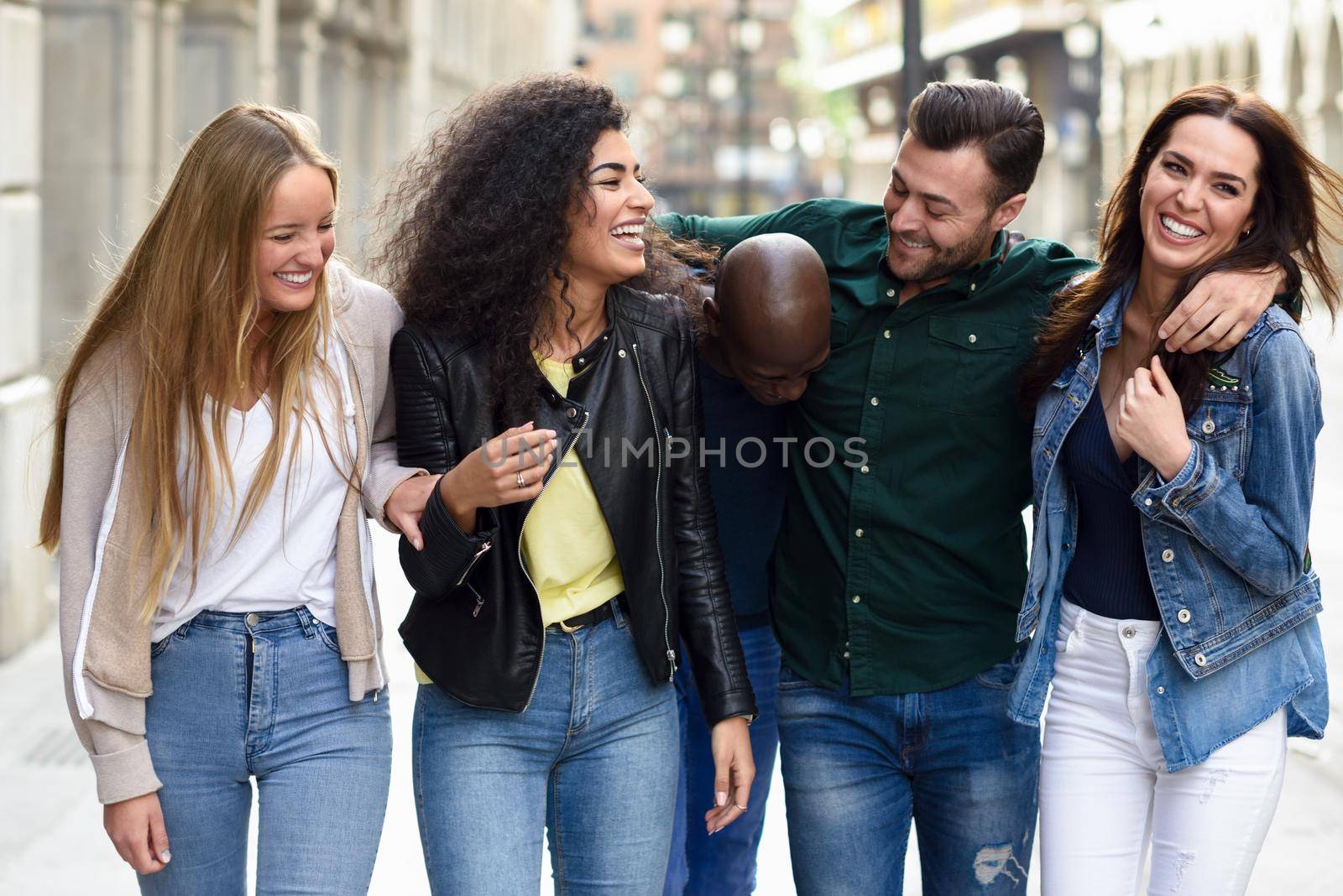 Multi-ethnic group of young people having fun together outdoors in urban background. group of people walking together