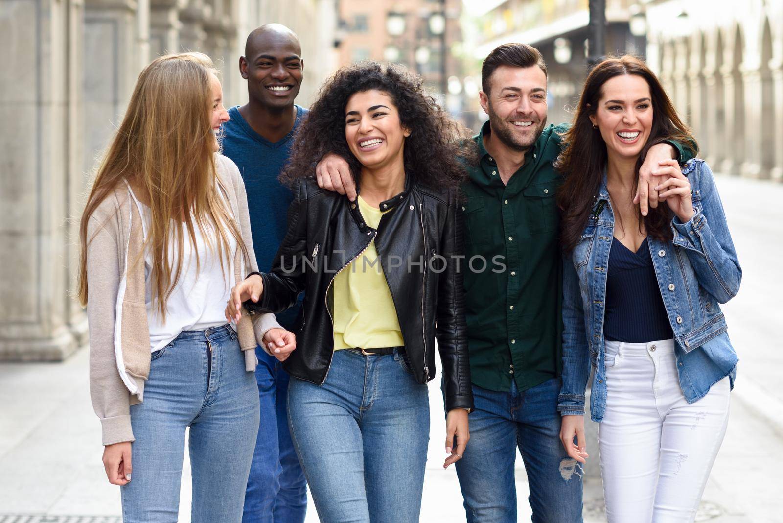 Multi-ethnic group of young people having fun together outdoors in urban background. group of people walking together