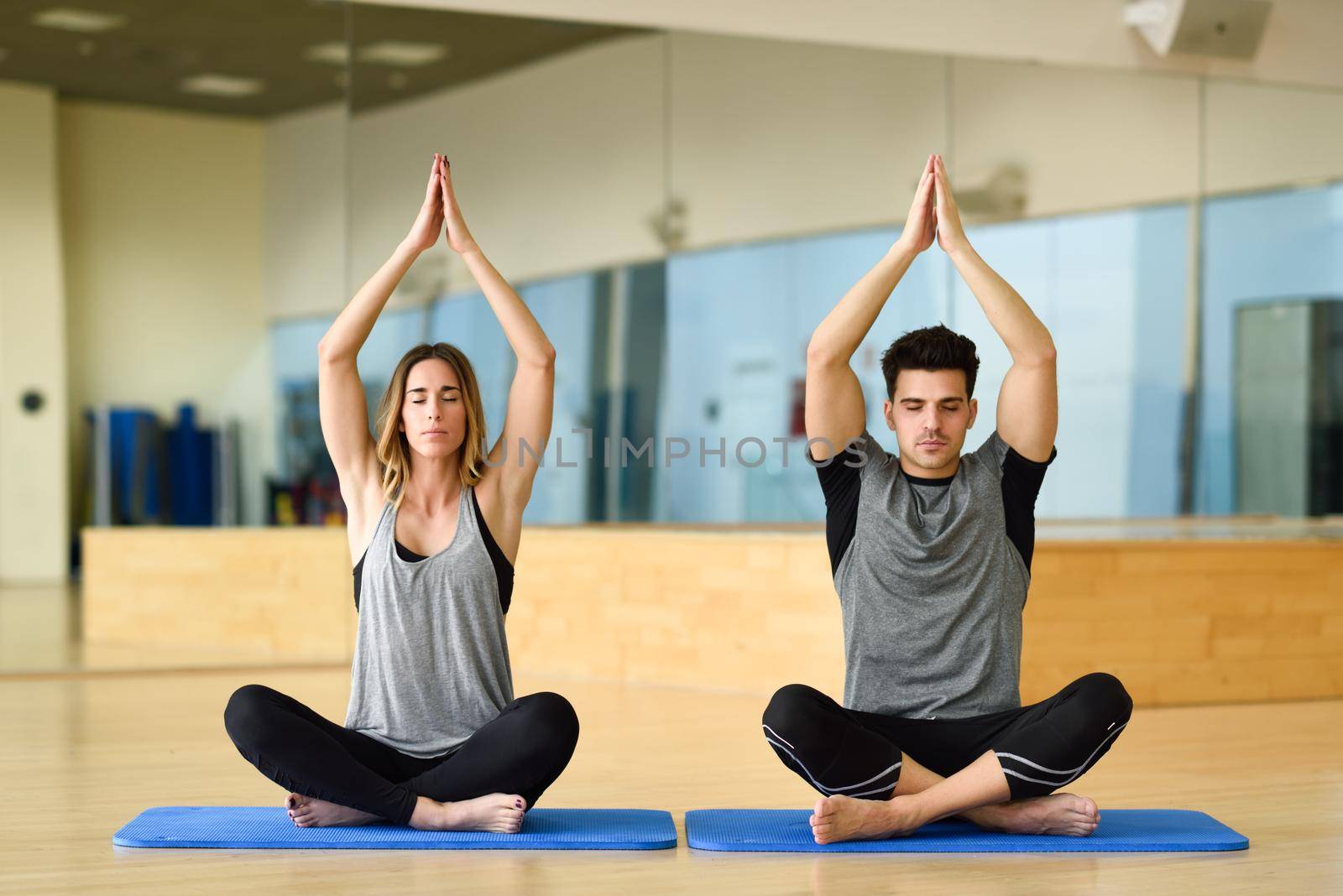 Young woman and man practicing yoga indoors by javiindy