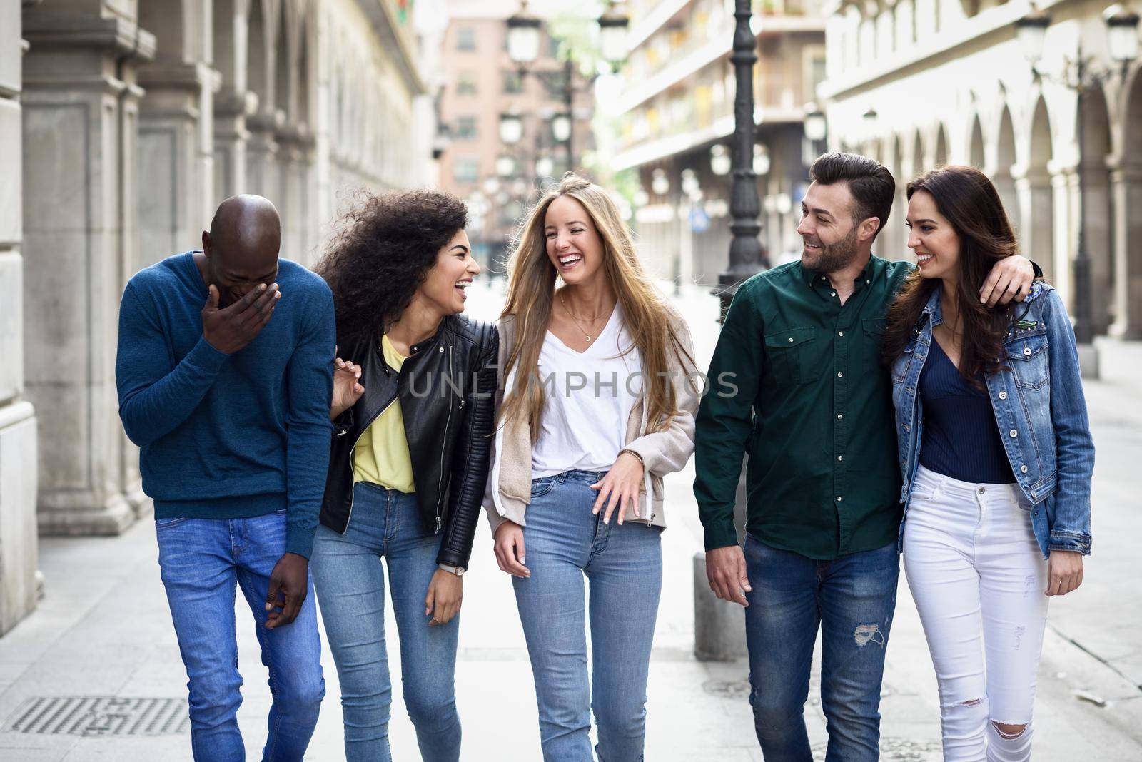 Multi-ethnic group of young people having fun together outdoors in urban background. group of people walking together