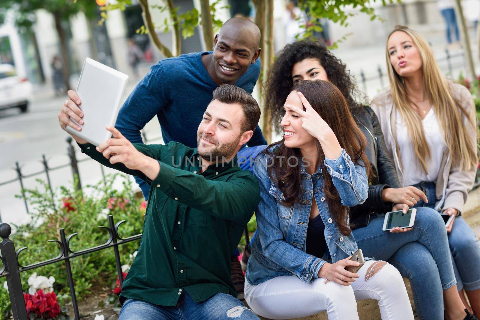 Multi-ethnic young people taking selfie together in urban background by javiindy
