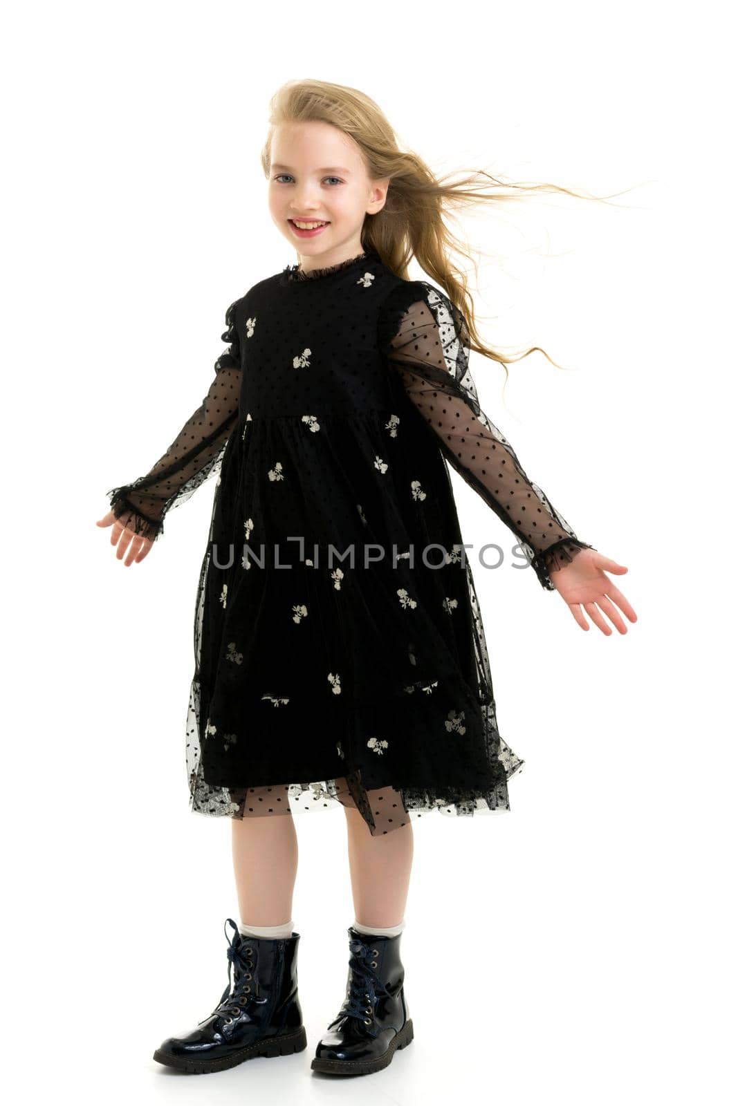 A strong wind blows on the face and clothes of a beautiful little girl of school age. Hair and clothes fluttering in the wind, and the girl is glad. Isolated on white background