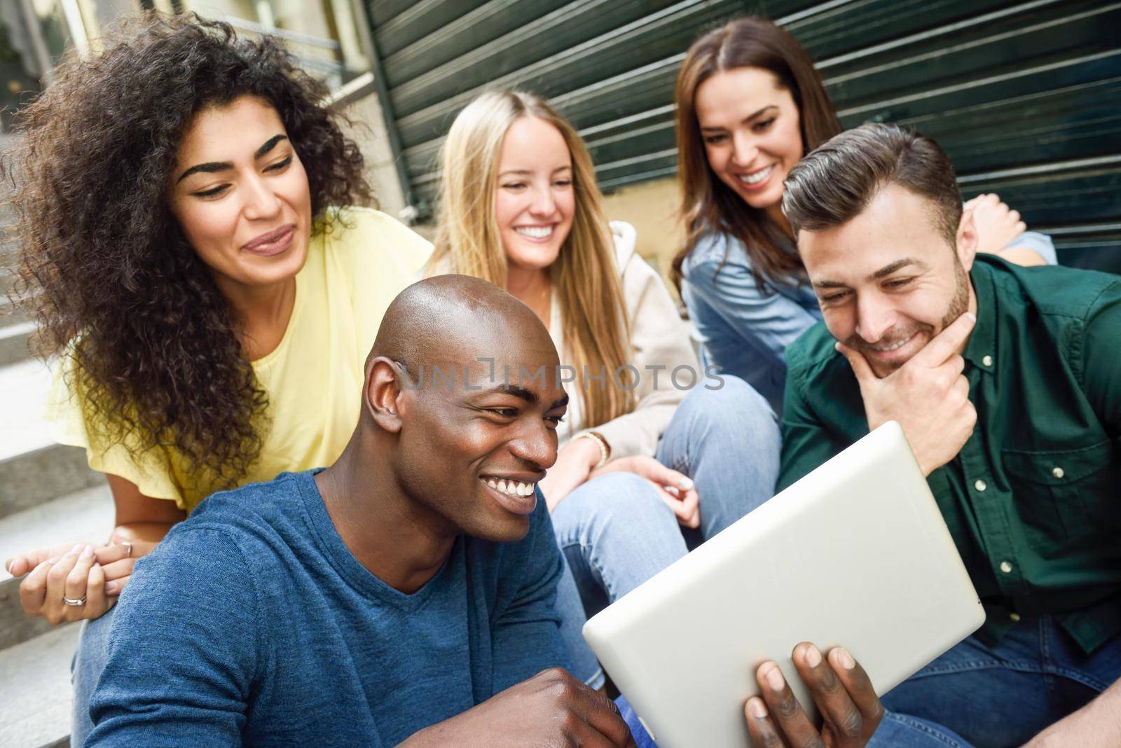 Multi-ethnic group of young people looking at a tablet computer by javiindy