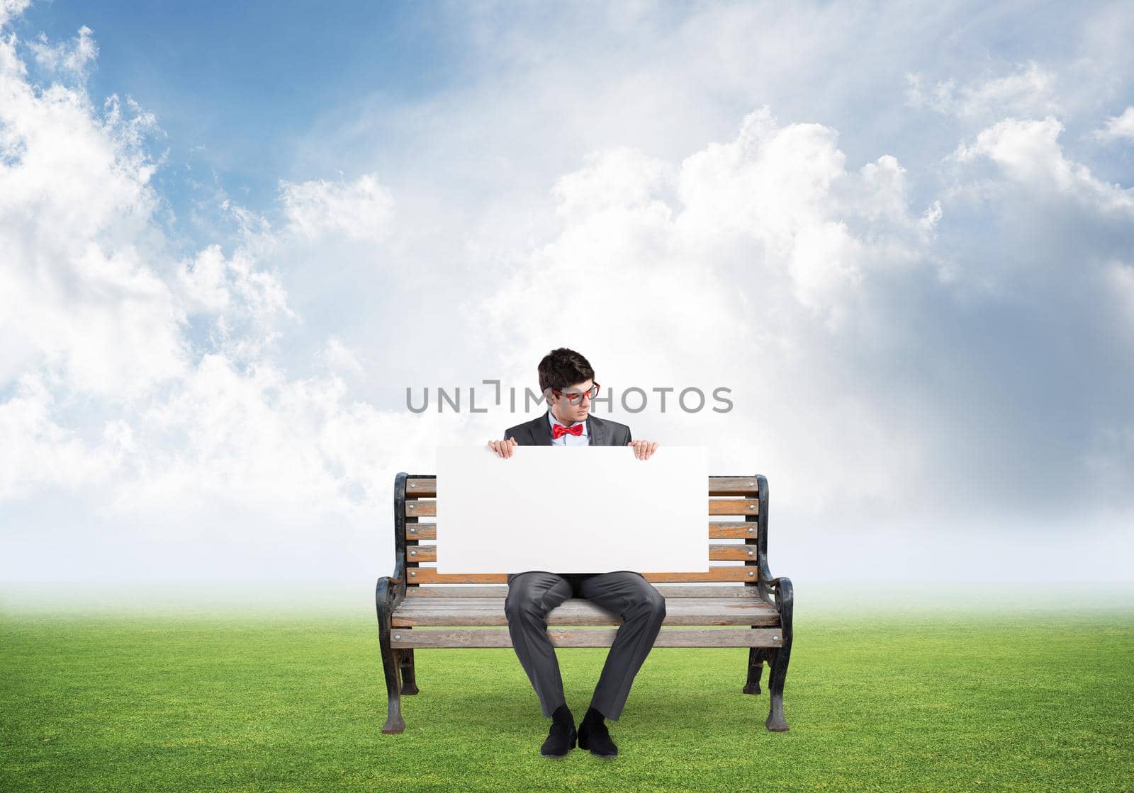 young businessman sits on a wooden bench with an empty banner