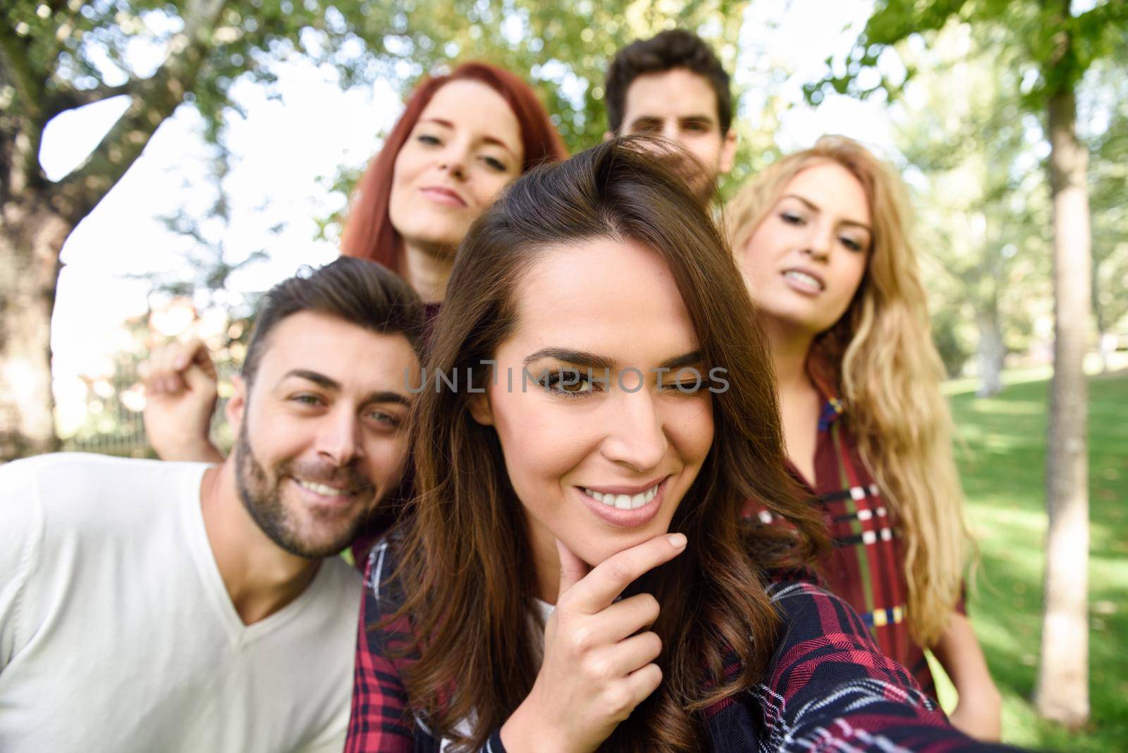 Group of young people together outdoors in urban background. Women and men sitting on stairs in the street wearing casual clothes.