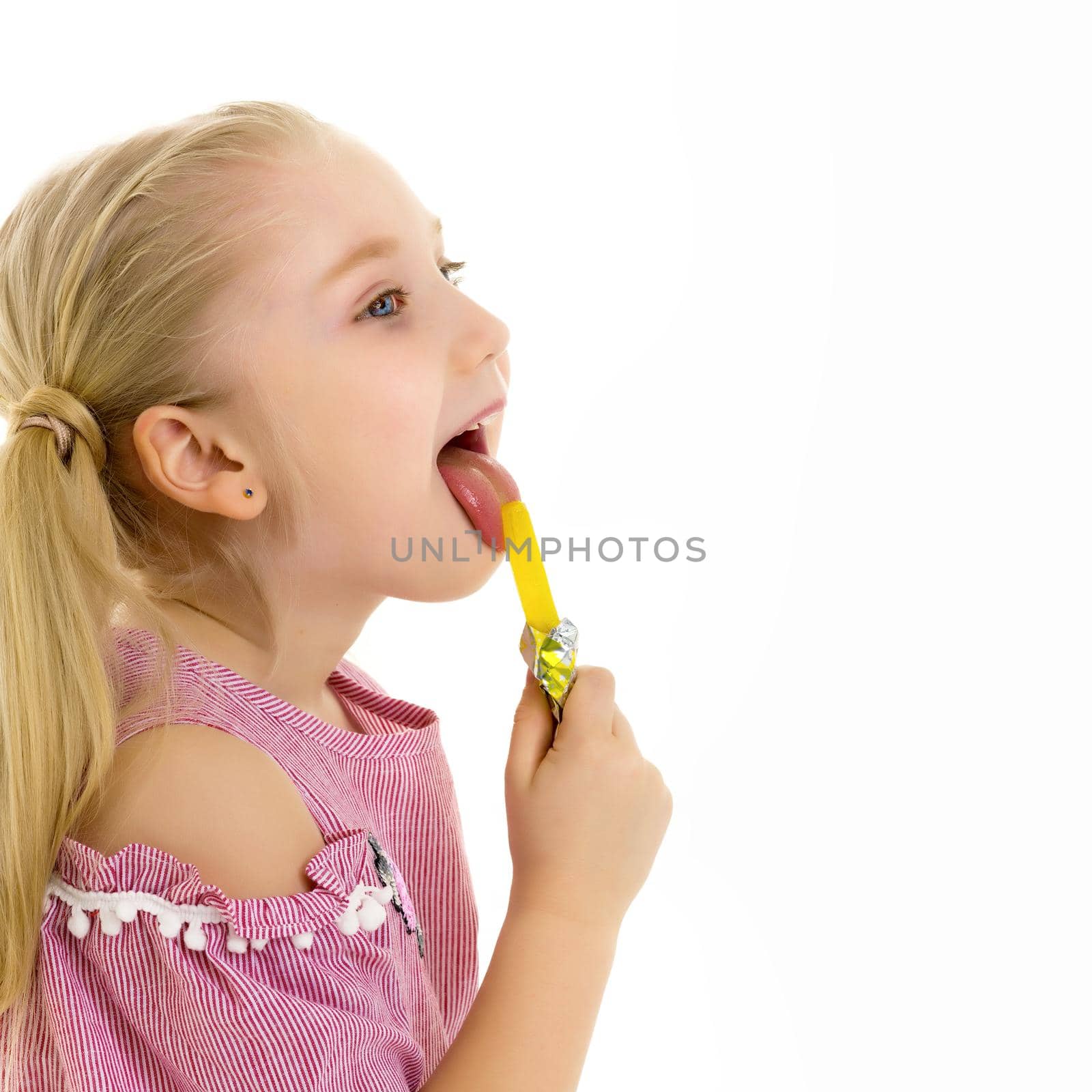 Cute little girl with great pleasure licks a candy. Happy childhood concept. Isolated over white background.