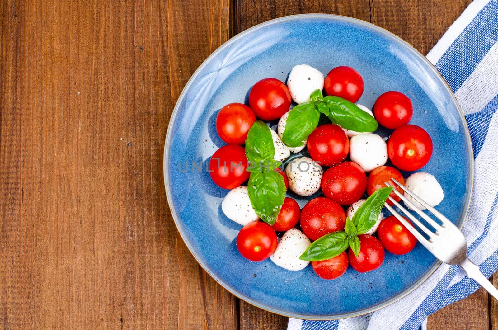 Delicious Italian caprese salad with basil, mozzarella and cherry tomatoes. Studio Photo