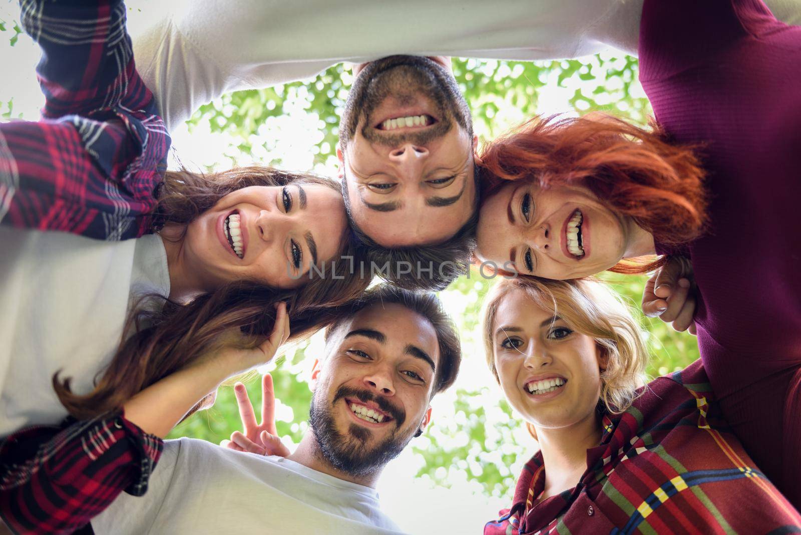 Group of young people together outdoors in urban background. Men and women looking down