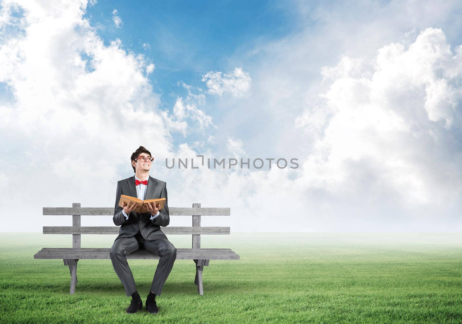 a young student sits on a wooden bench and holds a book. looks up
