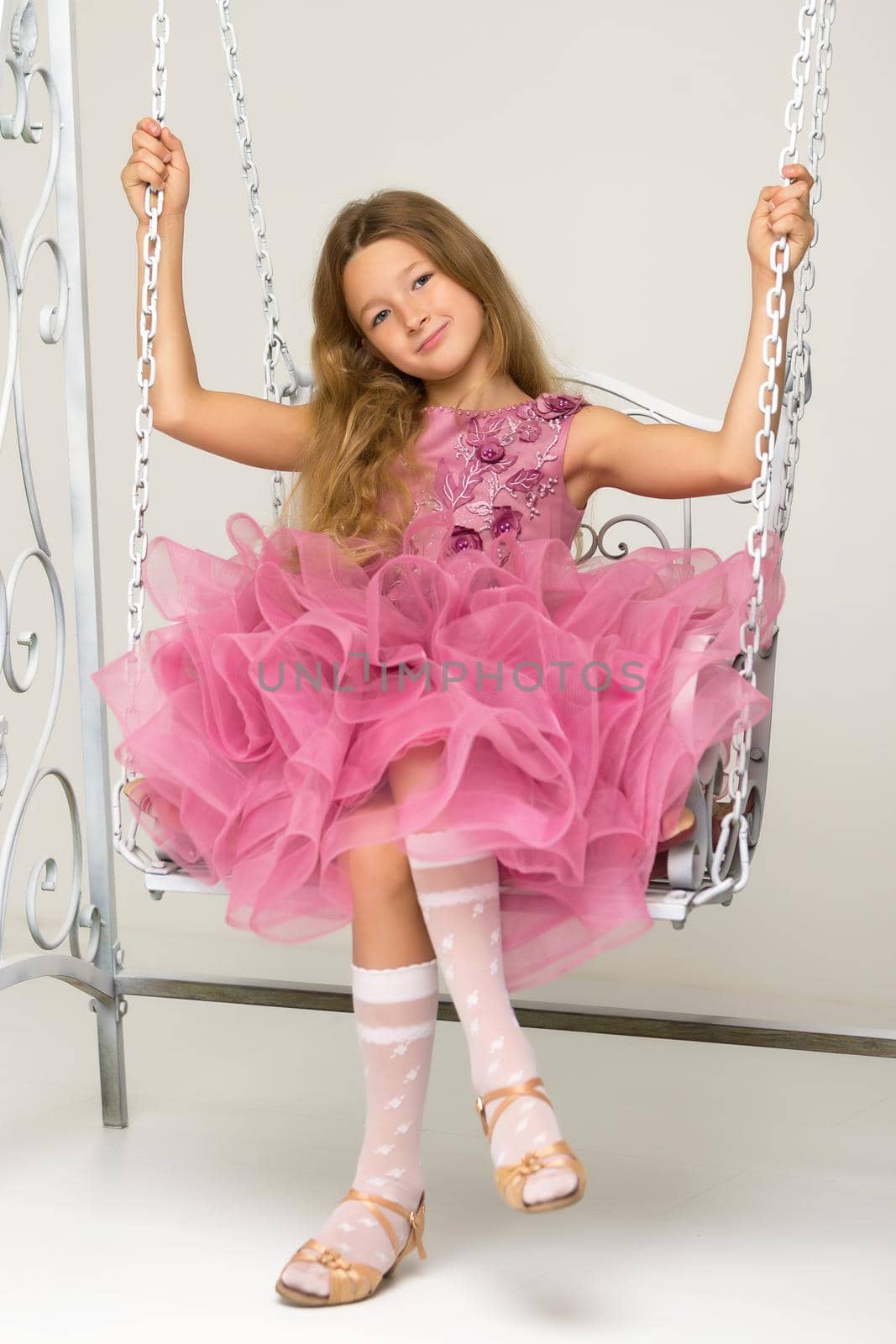 Happy little girl schoolgirl swinging on a swing. by kolesnikov_studio