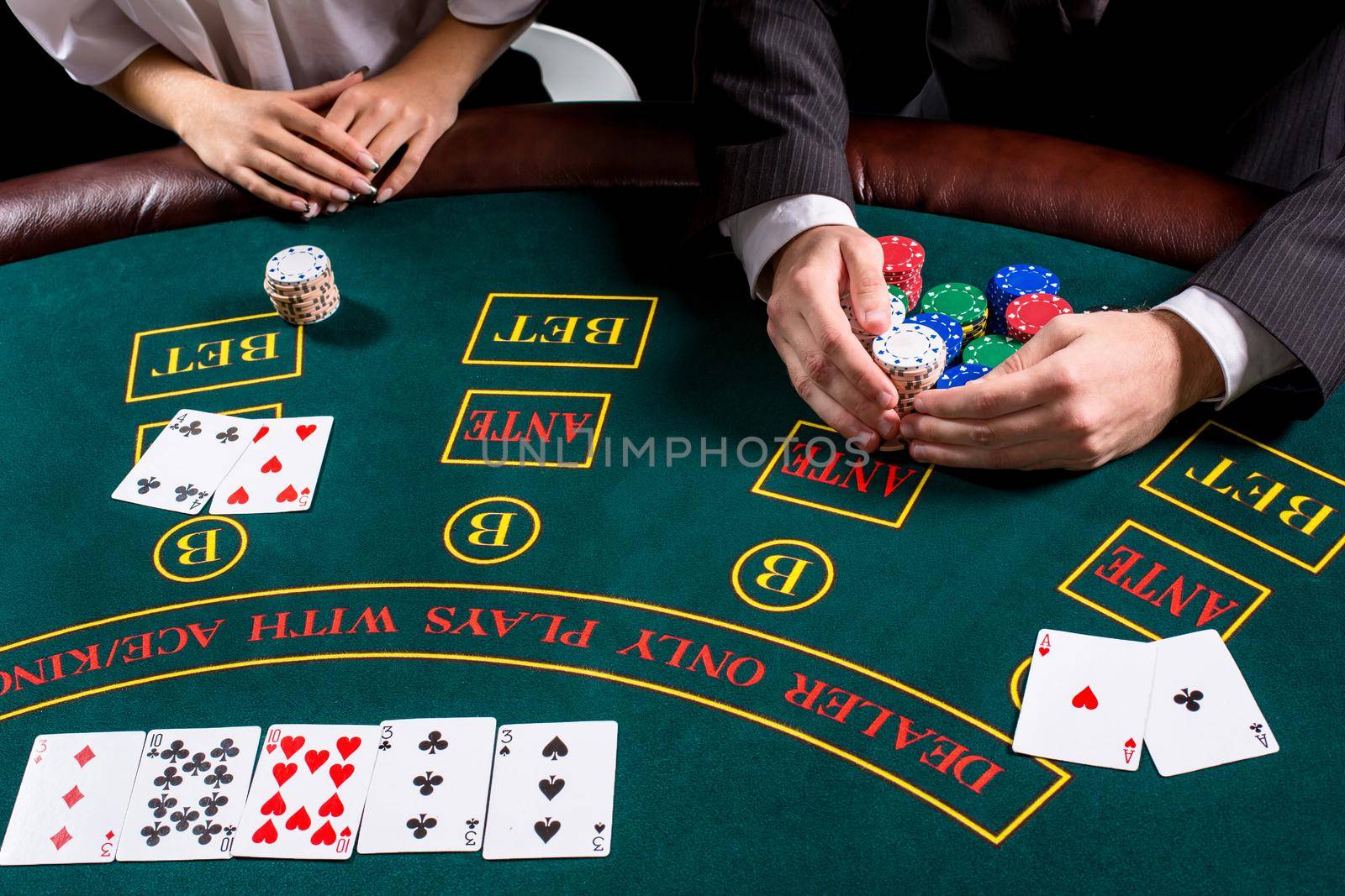 couple playing poker at the table. The blonde girl and a guy in a suit. close up hands. take chips won