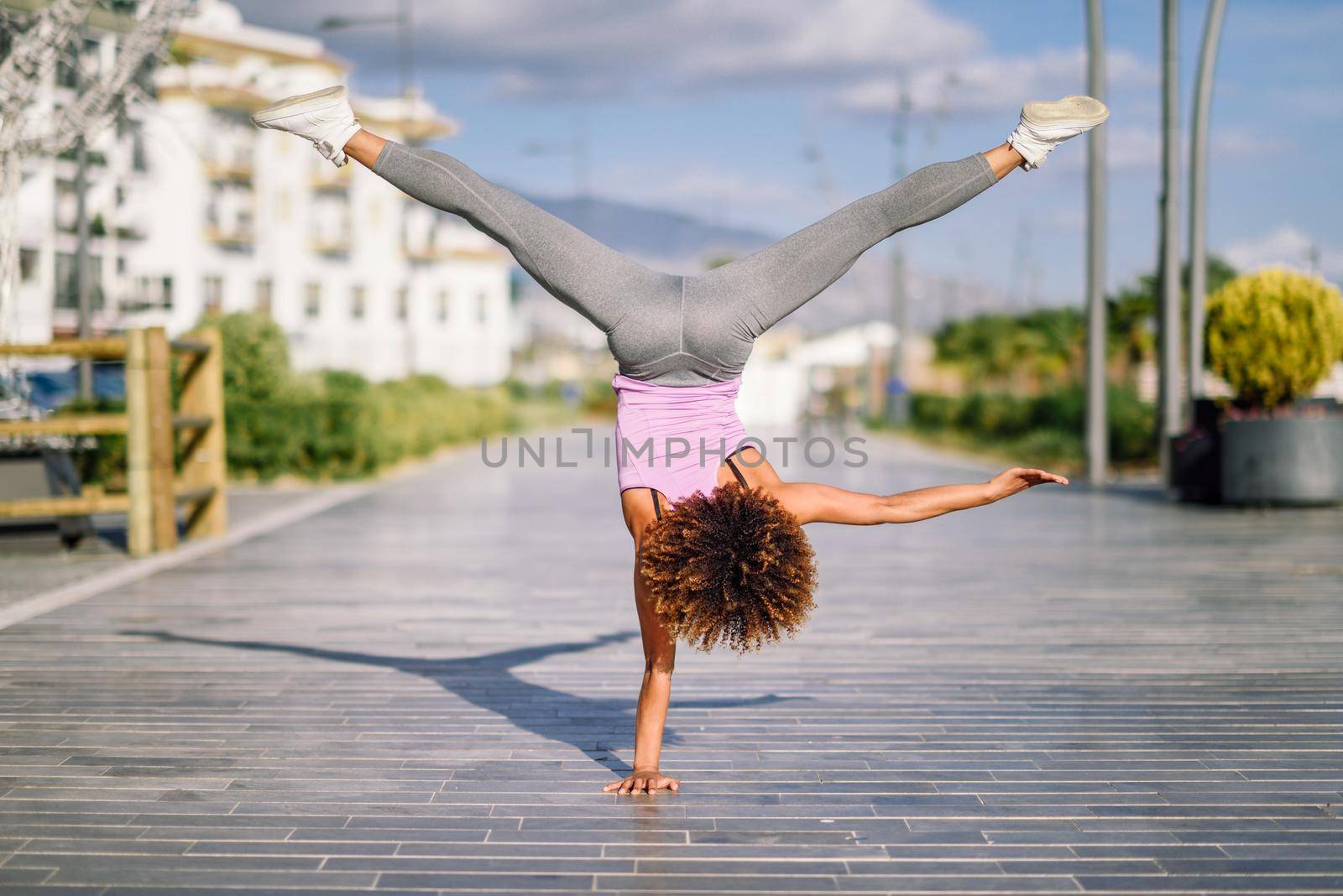Black fit woman doing fitness acrobatics in urban background. Young female exercising and working out hard.